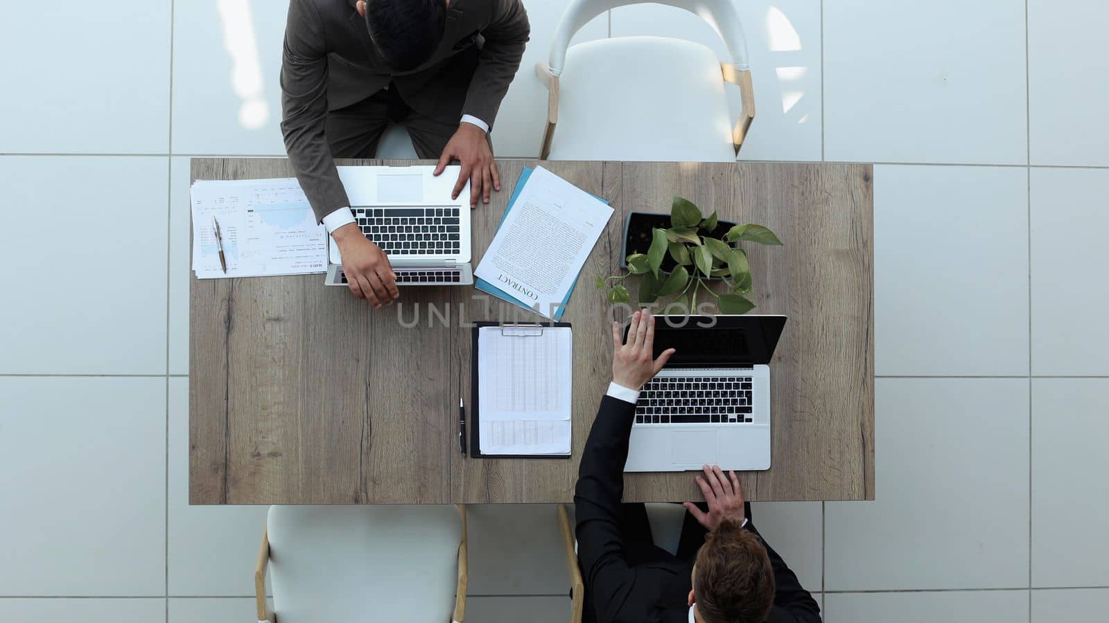 two businessmen sitting on a chair and watching something on a laptop