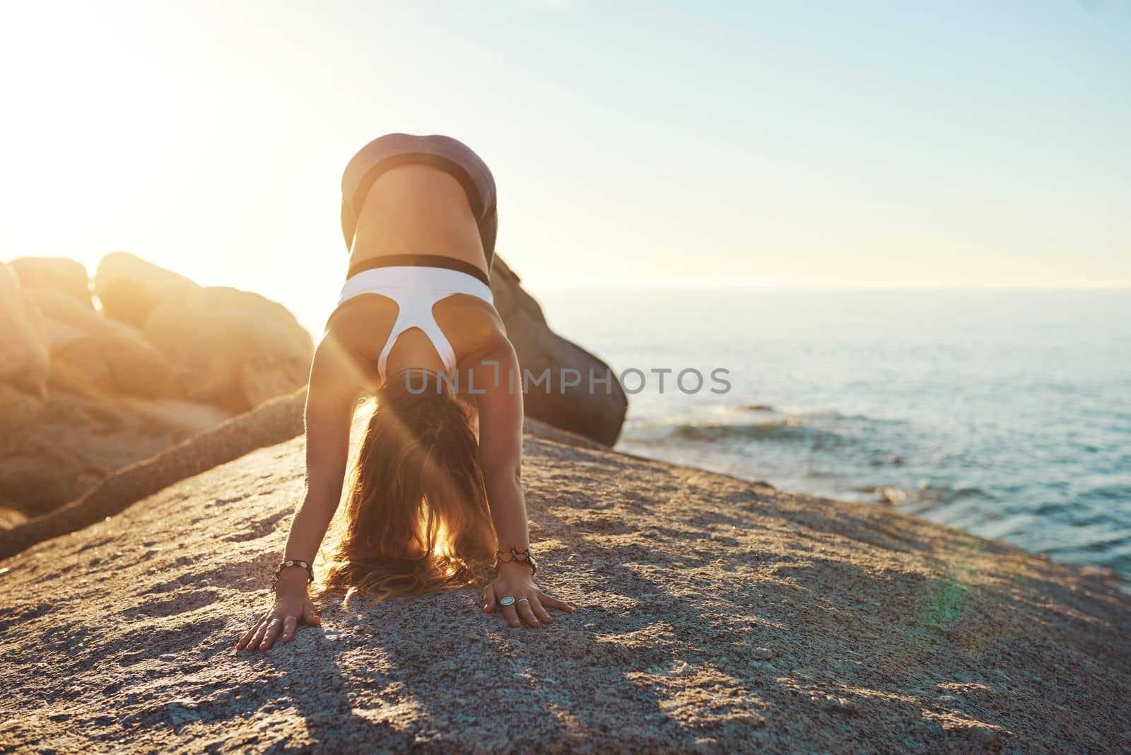 Because yoga will get you back on track. an athletic young woman practicing yoga on the beach. by YuriArcurs