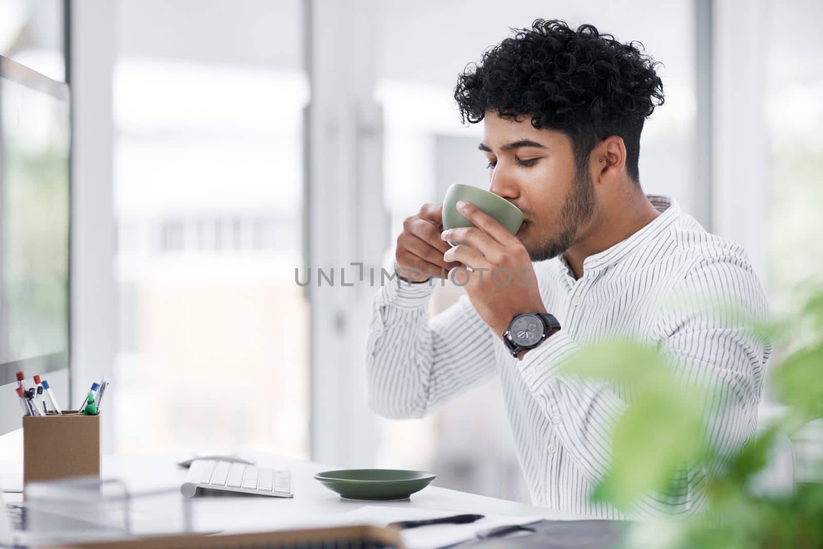 I can achieve it all with coffee by my side. Portrait of a young businessman drinking coffee while working in an office. by YuriArcurs