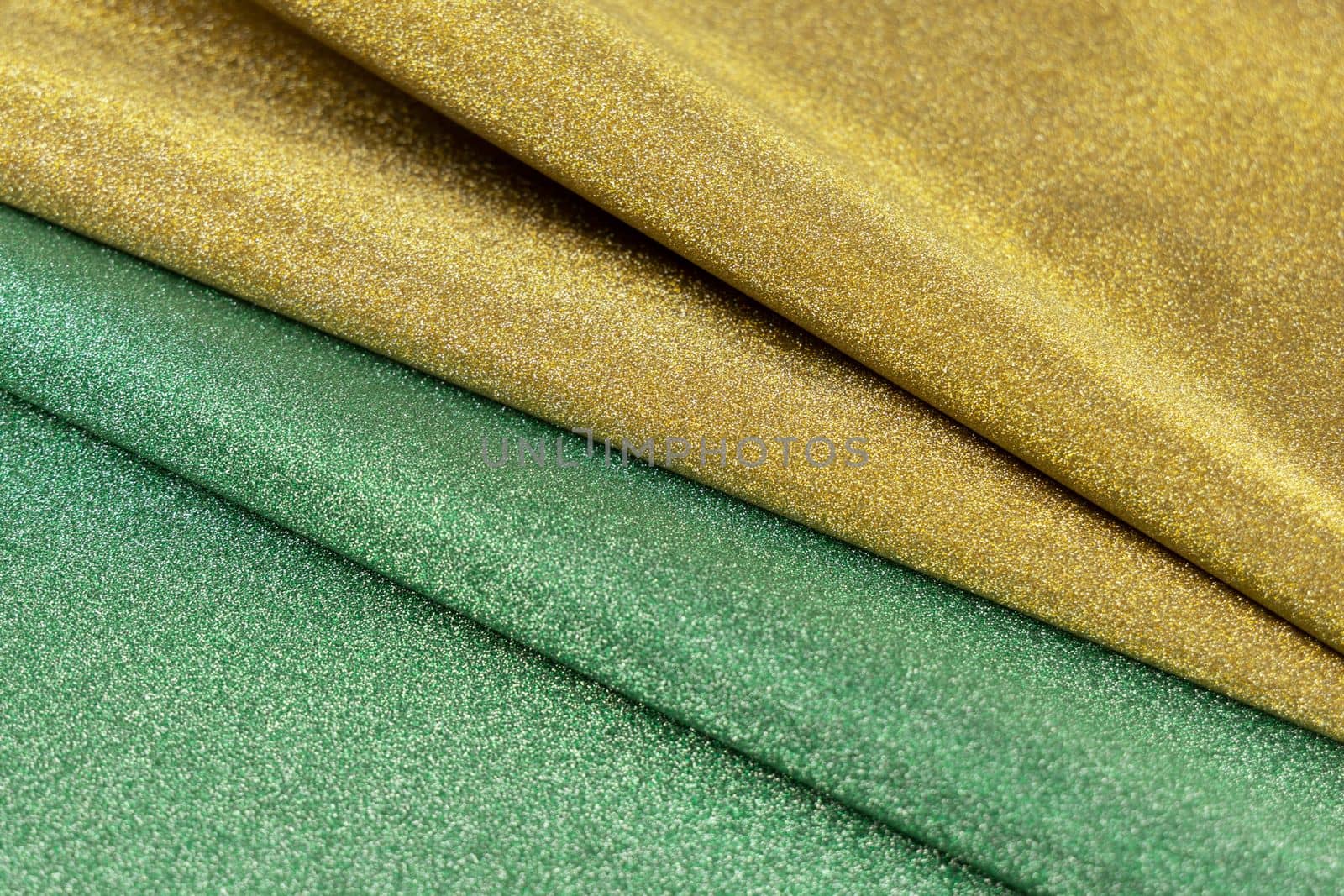 Golden and green wave shiny glitter paper texture. Shining luxurious fabric. Glimmering light green golden color, christmas background