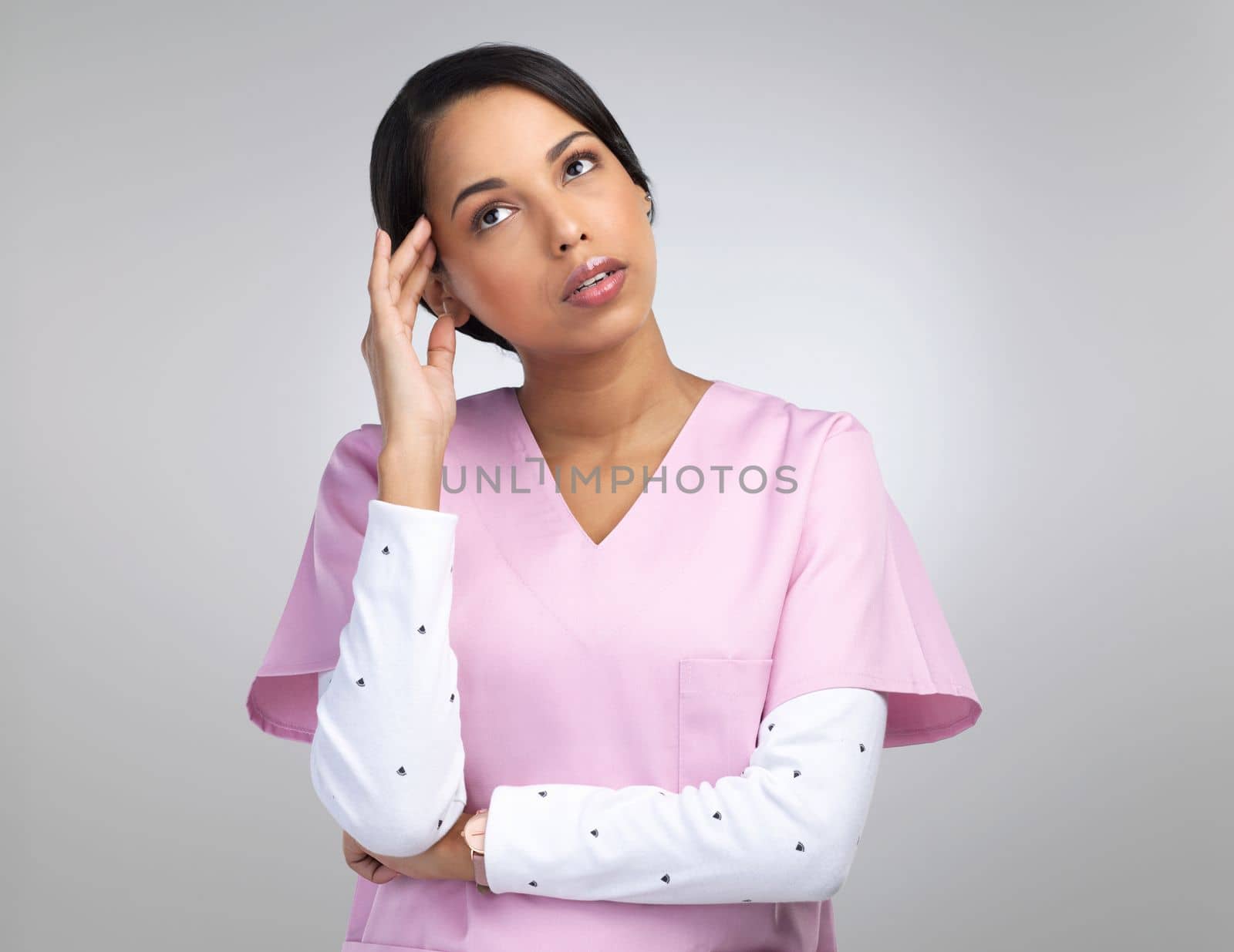 Being a doctor comes with its own stresses. an attractive young female healthcare worker looking stressed while standing in studio against a grey background. by YuriArcurs