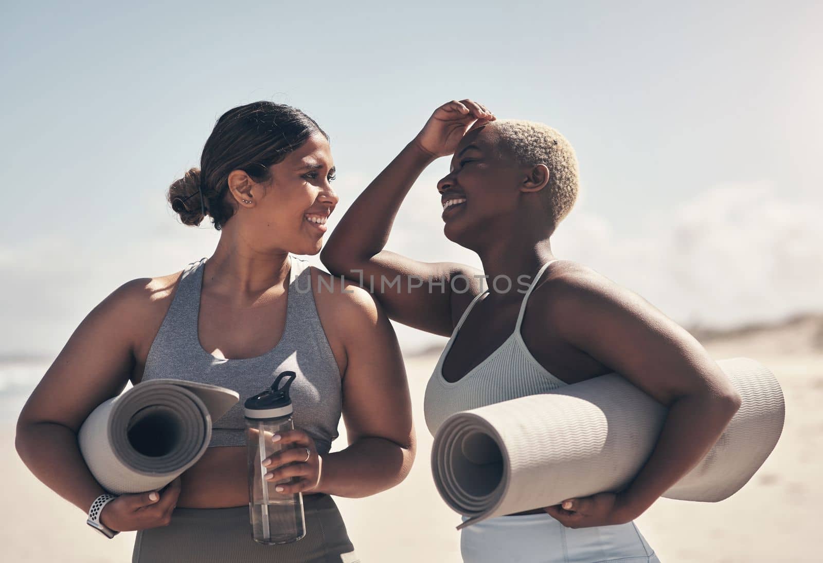 Yoga allows us to move at our own pace. two young women holding their yoga mats while on the beach