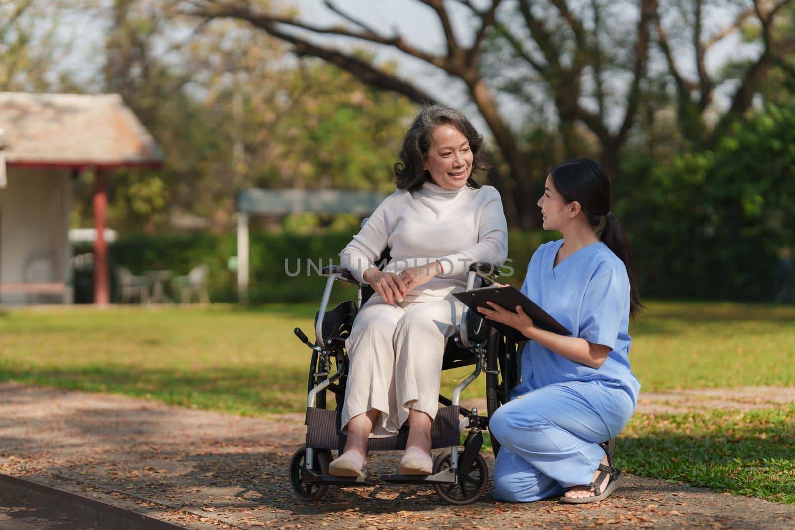 Elderly asian senior woman on wheelchair with nurse. Nursing home hospital garden concept by itchaznong