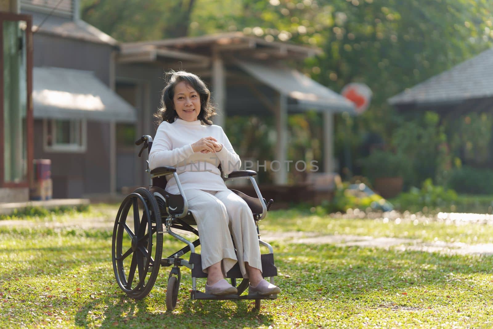 Happy senior asian women in wheelchair at home garden