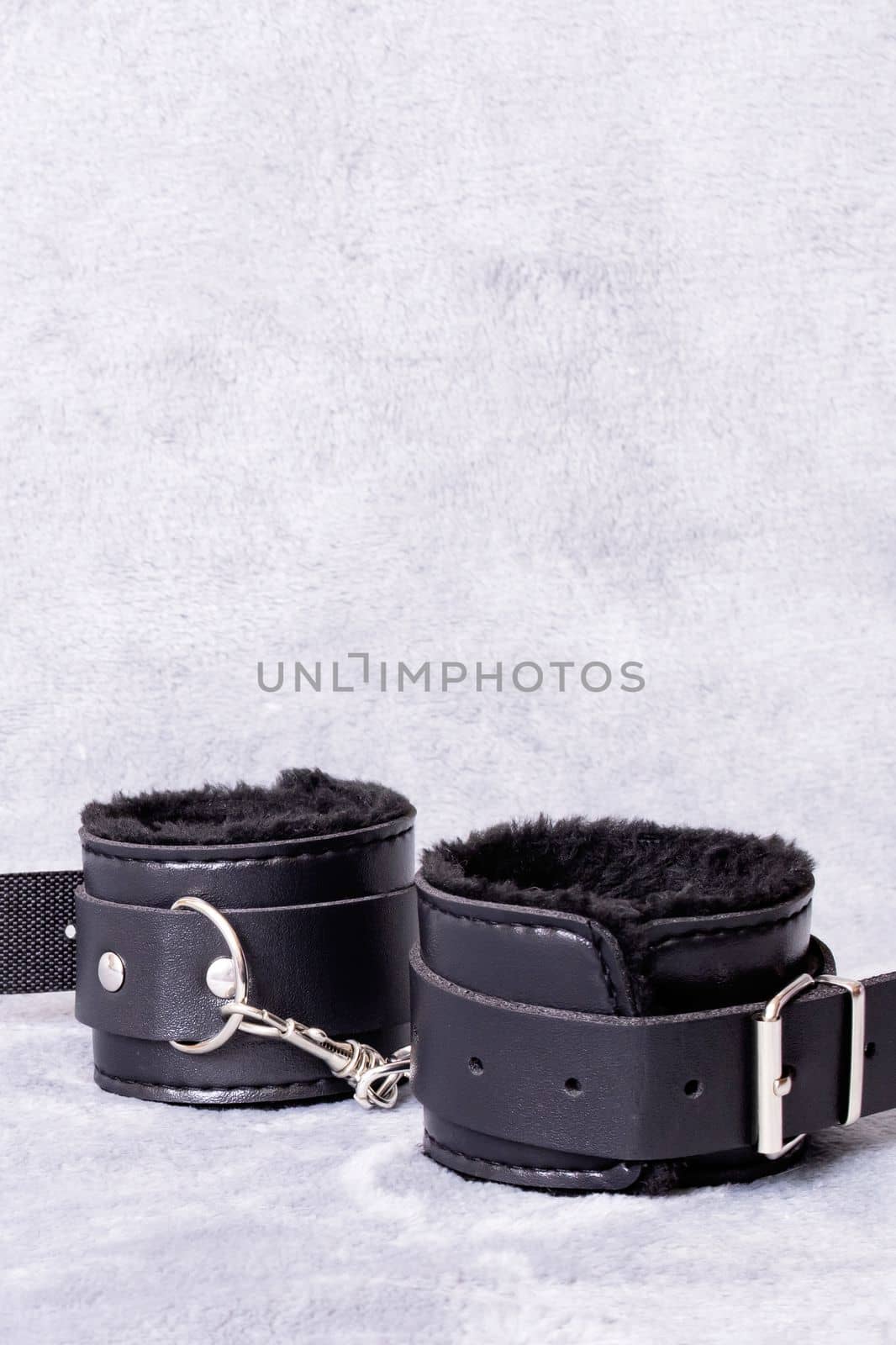 Black leather handcuffs on a gray background, copy space