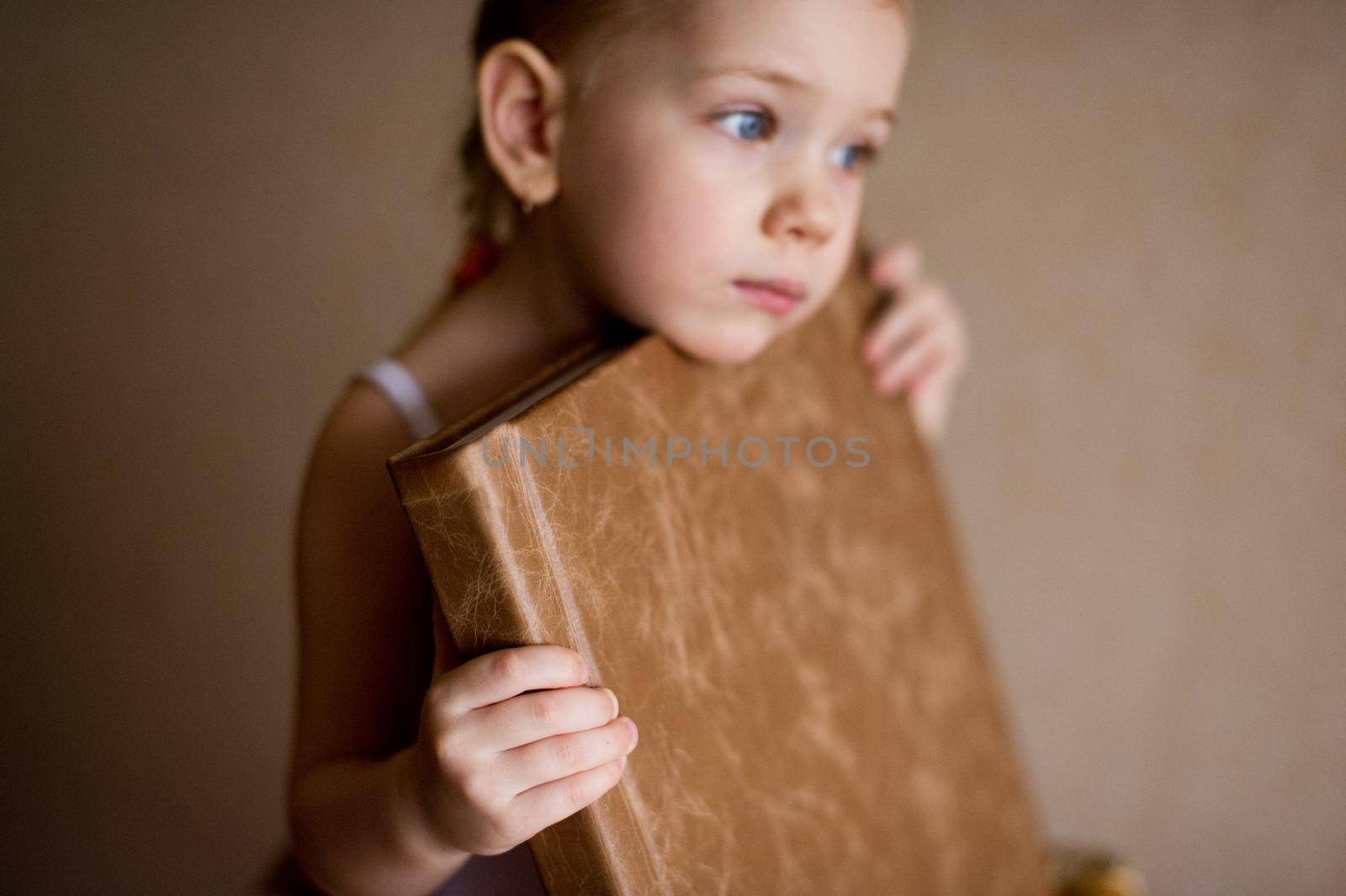 a little girl is holding a photo book in natural brown leather