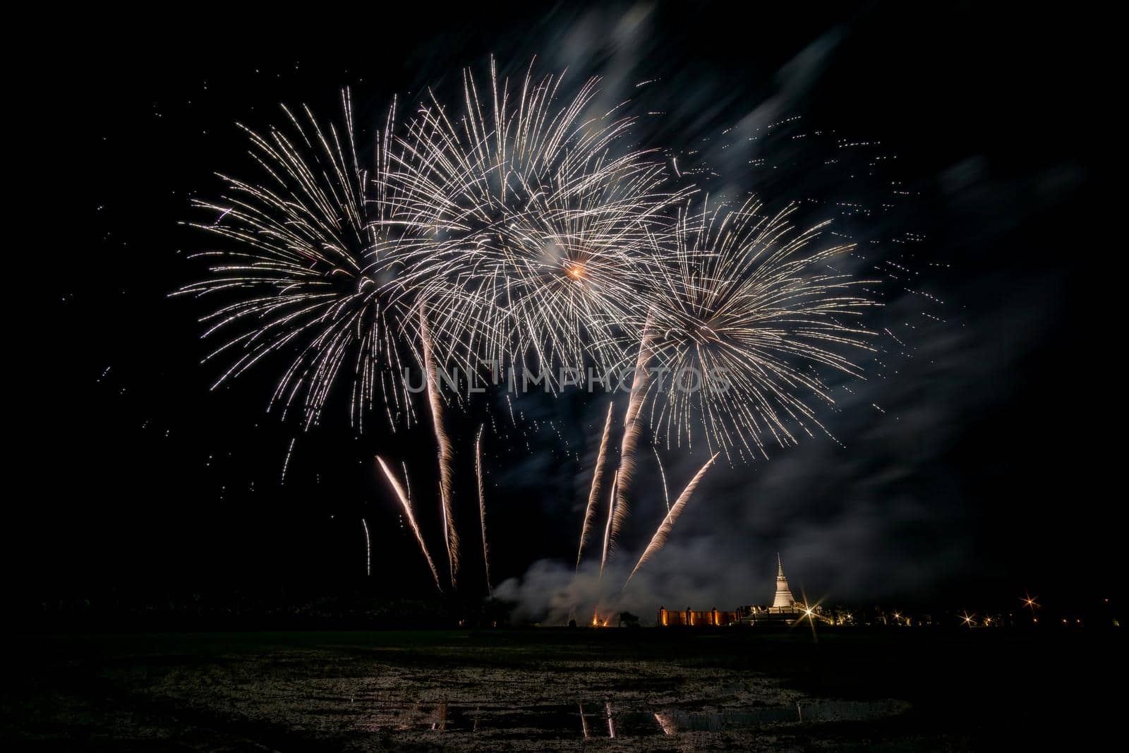 Huge, colorful fireworks over the rice fields at dusk.