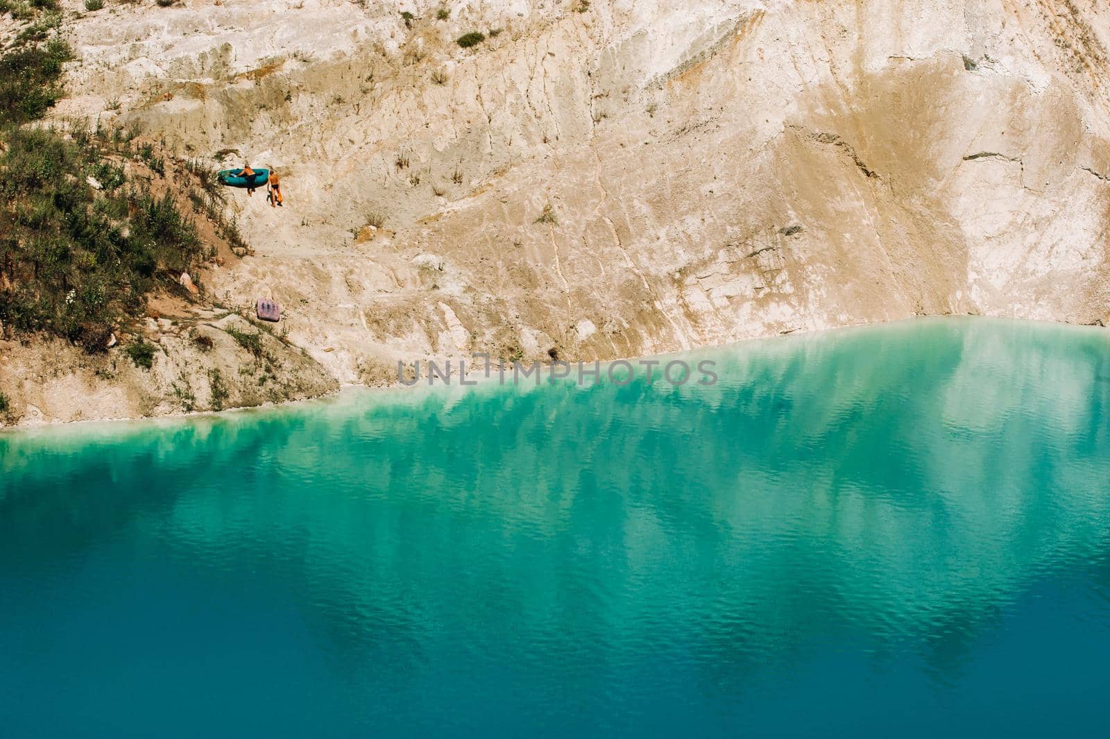 Vaukavysk chalk pits or Belarusian Maldives are beautiful saturated blue lakes.Two tourists pull a boat out of the water Belarus.