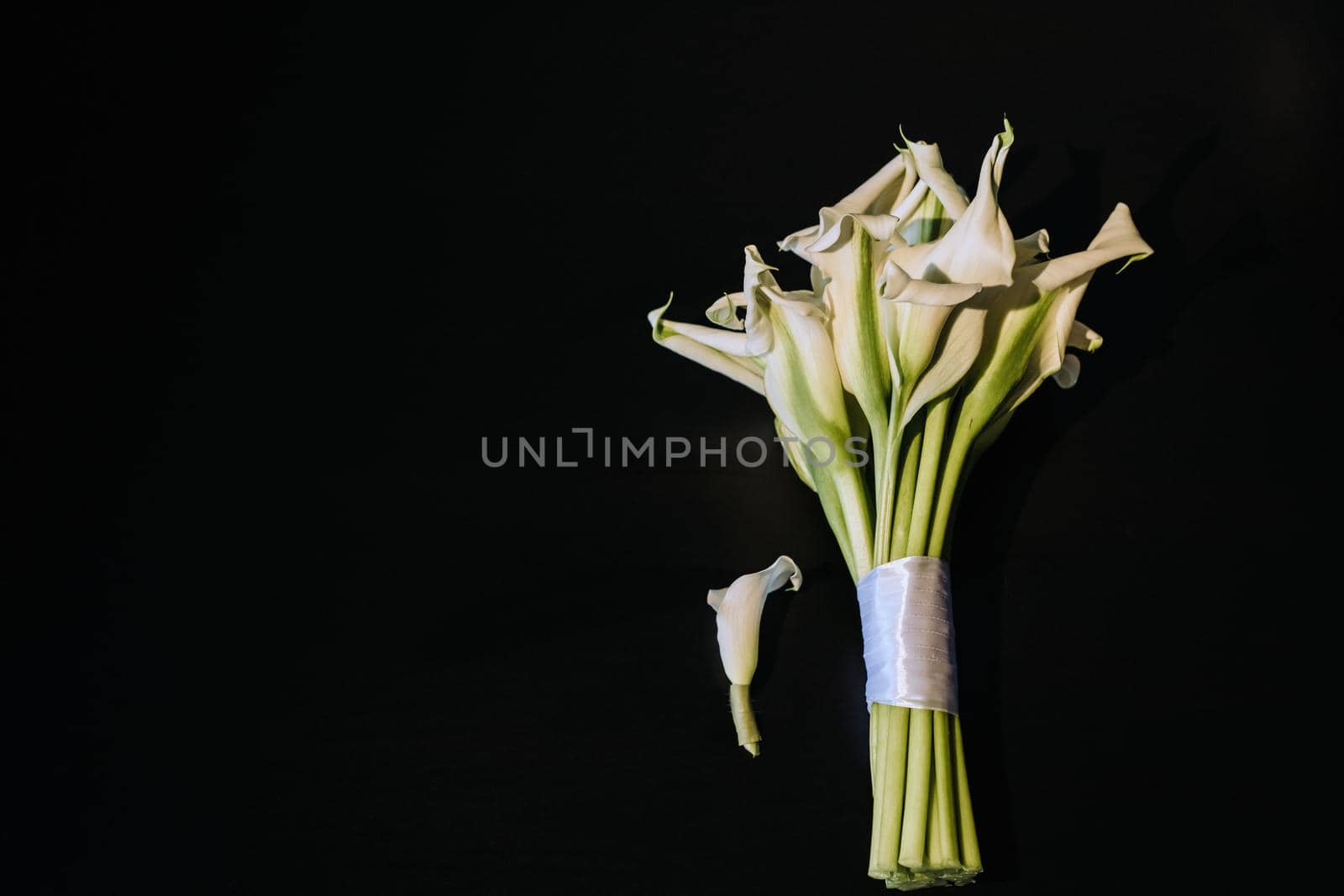 Wedding bouquet of white Calla lilies on a black background.