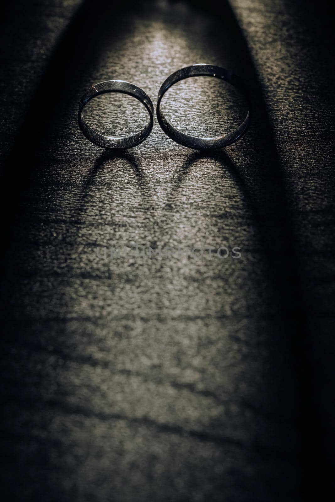 Close-up of two gold wedding rings on a black background by Lobachad