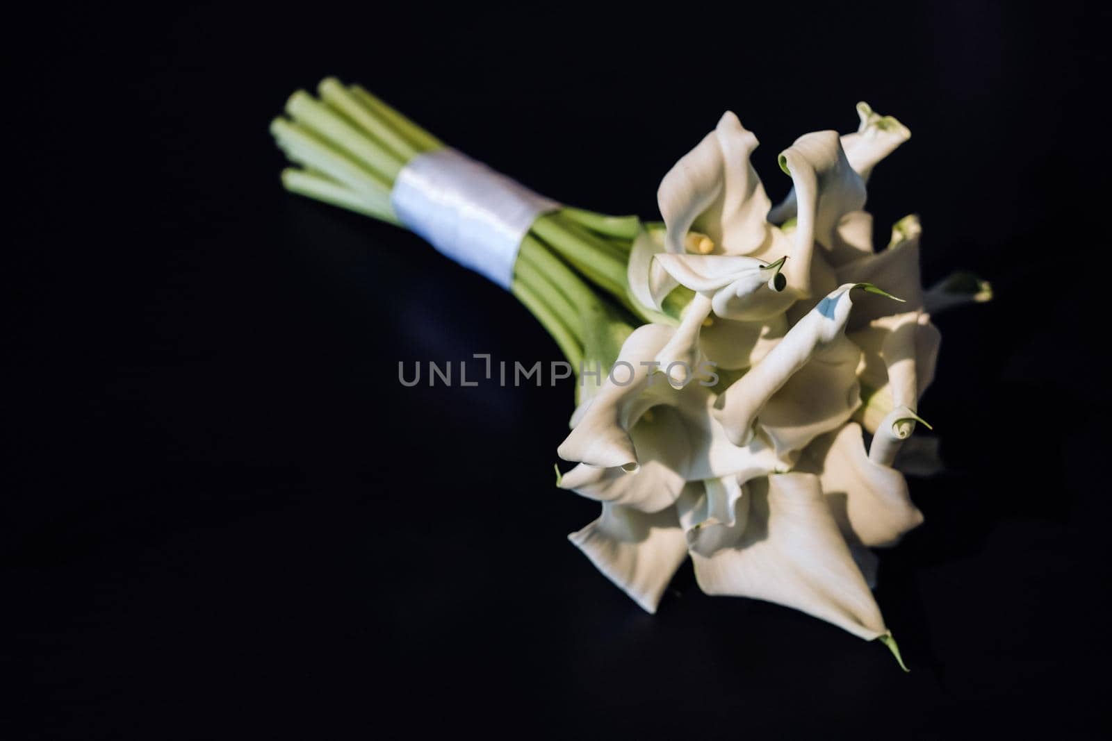 Wedding bouquet of white Calla lilies on a black background.