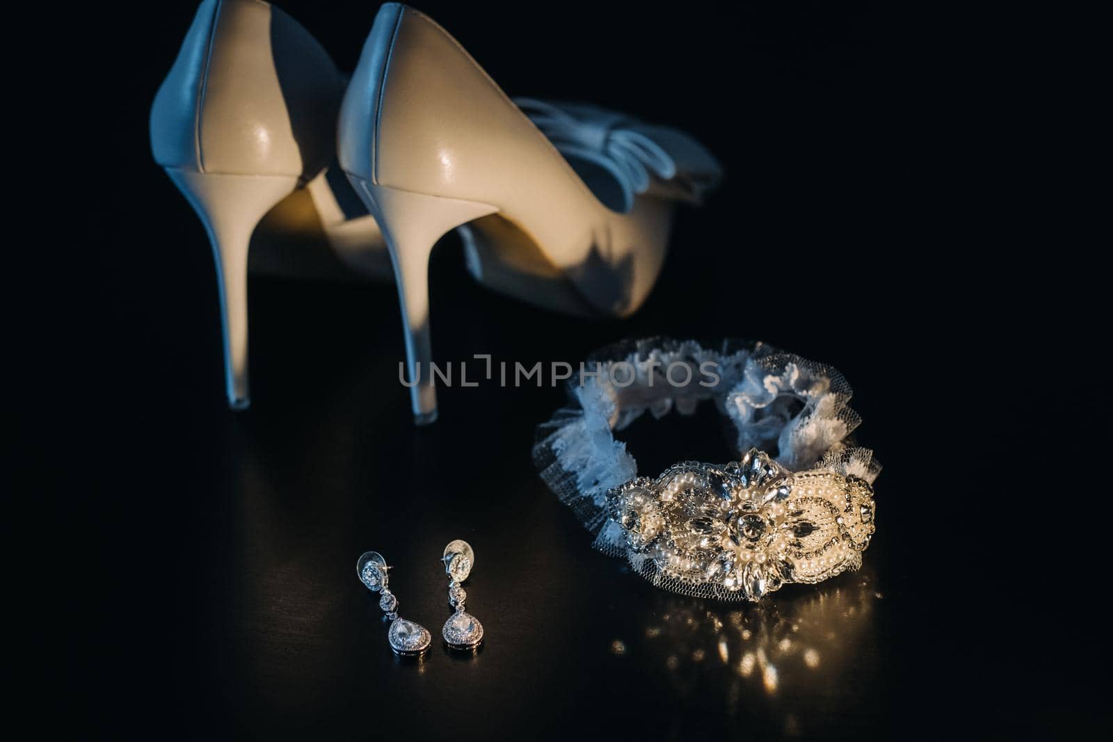 white wedding shoes and garter belt with earrings on a black background by Lobachad