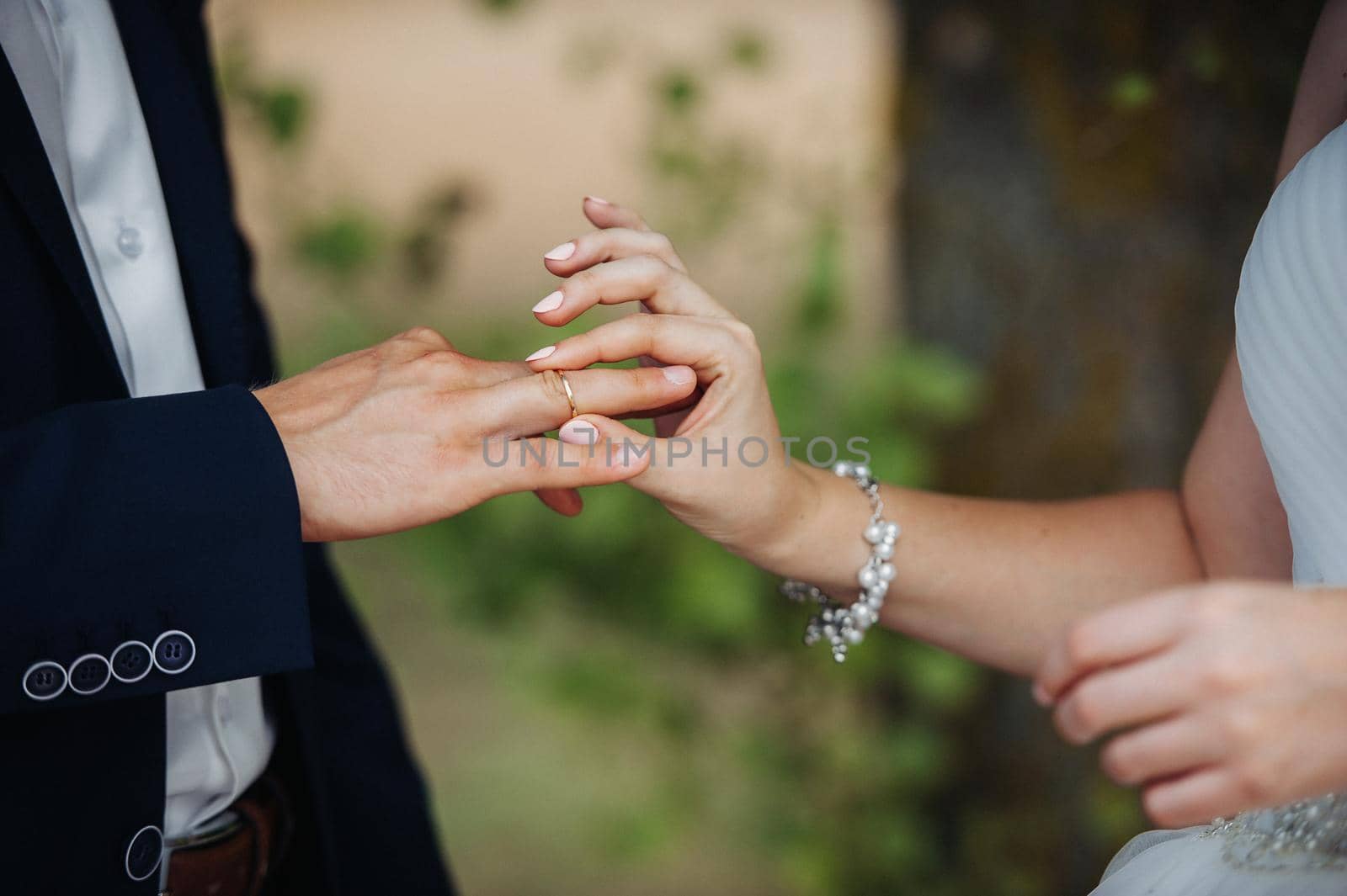 On the wedding day, the bride puts an engagement ring on the groom's finger.