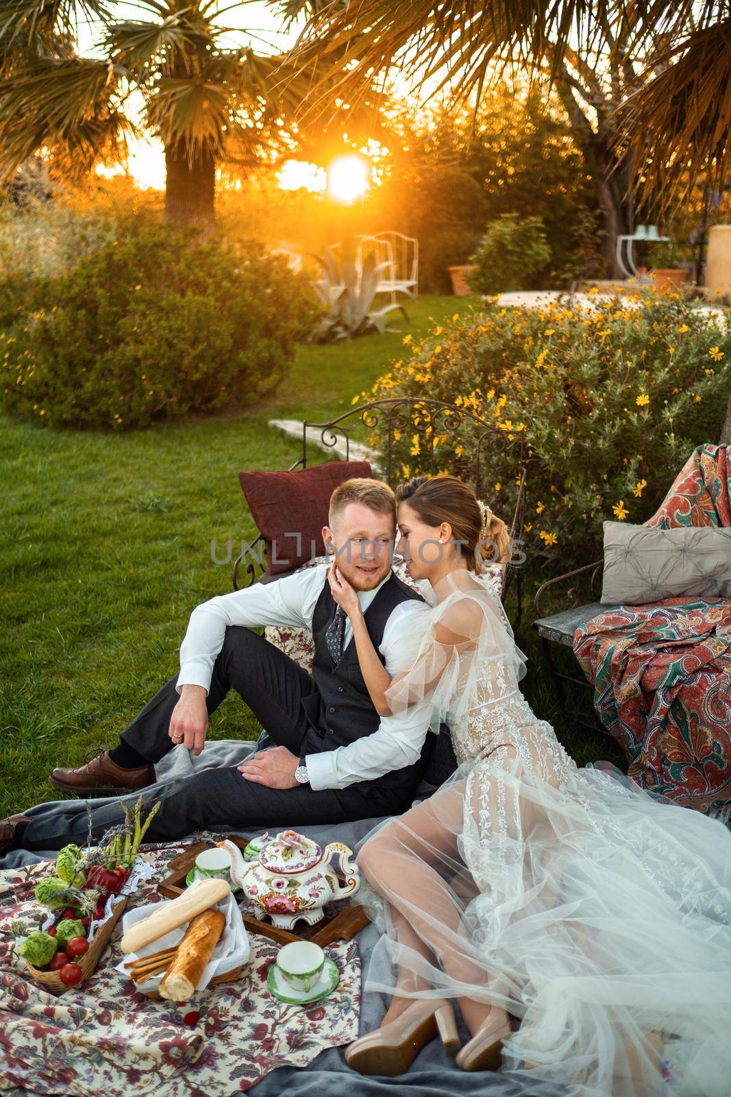 Newlyweds ' dinner on the lawn at sunset.A couple sits and drinks tea at sunset in France by Lobachad