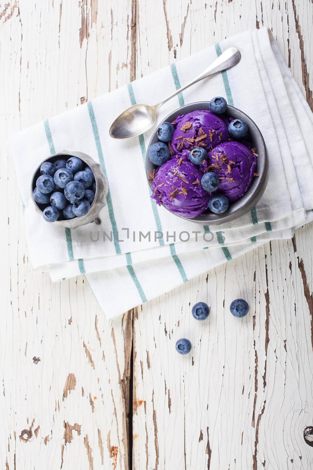 Fresh blueberry ice cream inside a pewter cup on old white wooden table