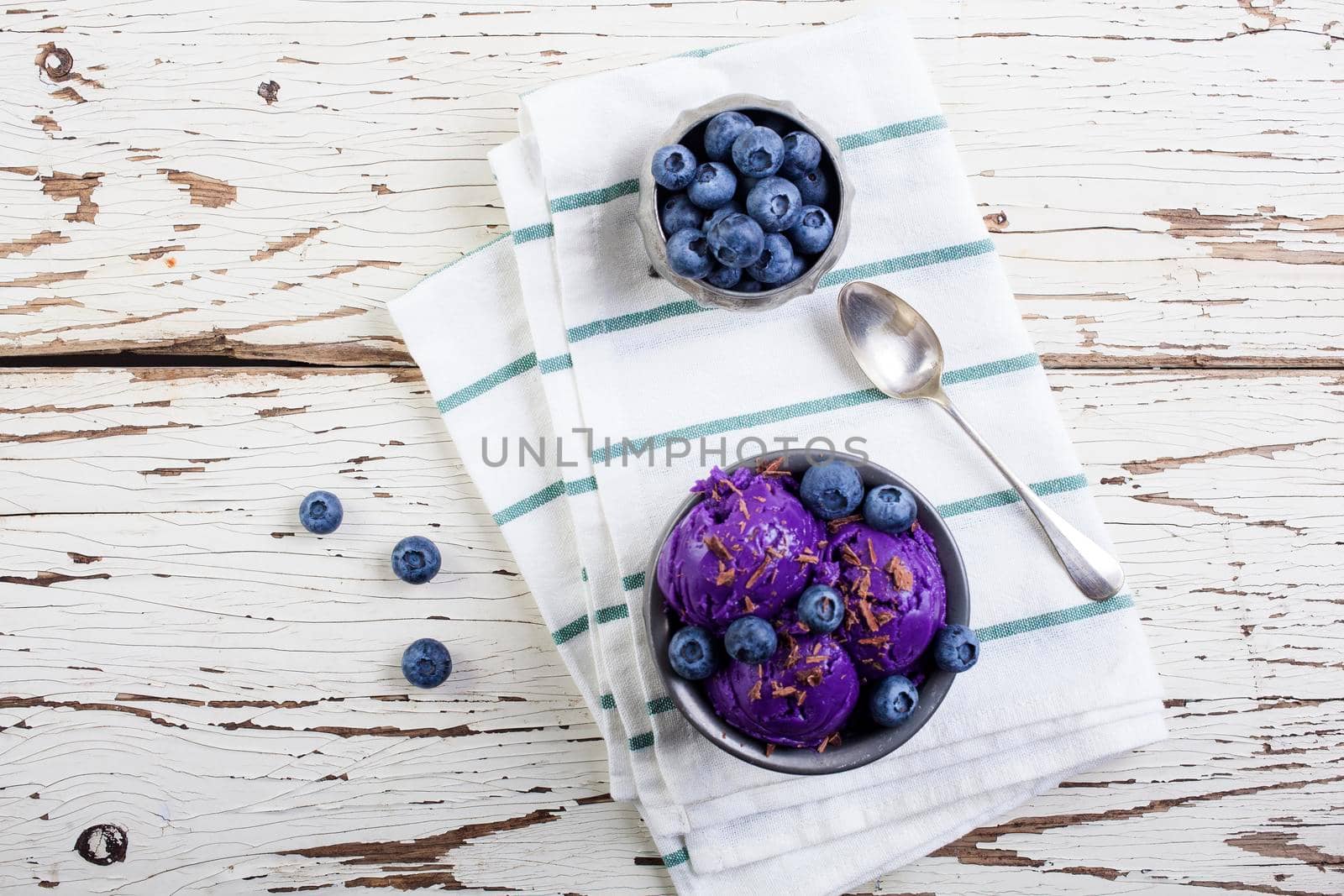 Fresh blueberry ice cream inside a pewter cup on old white wooden table