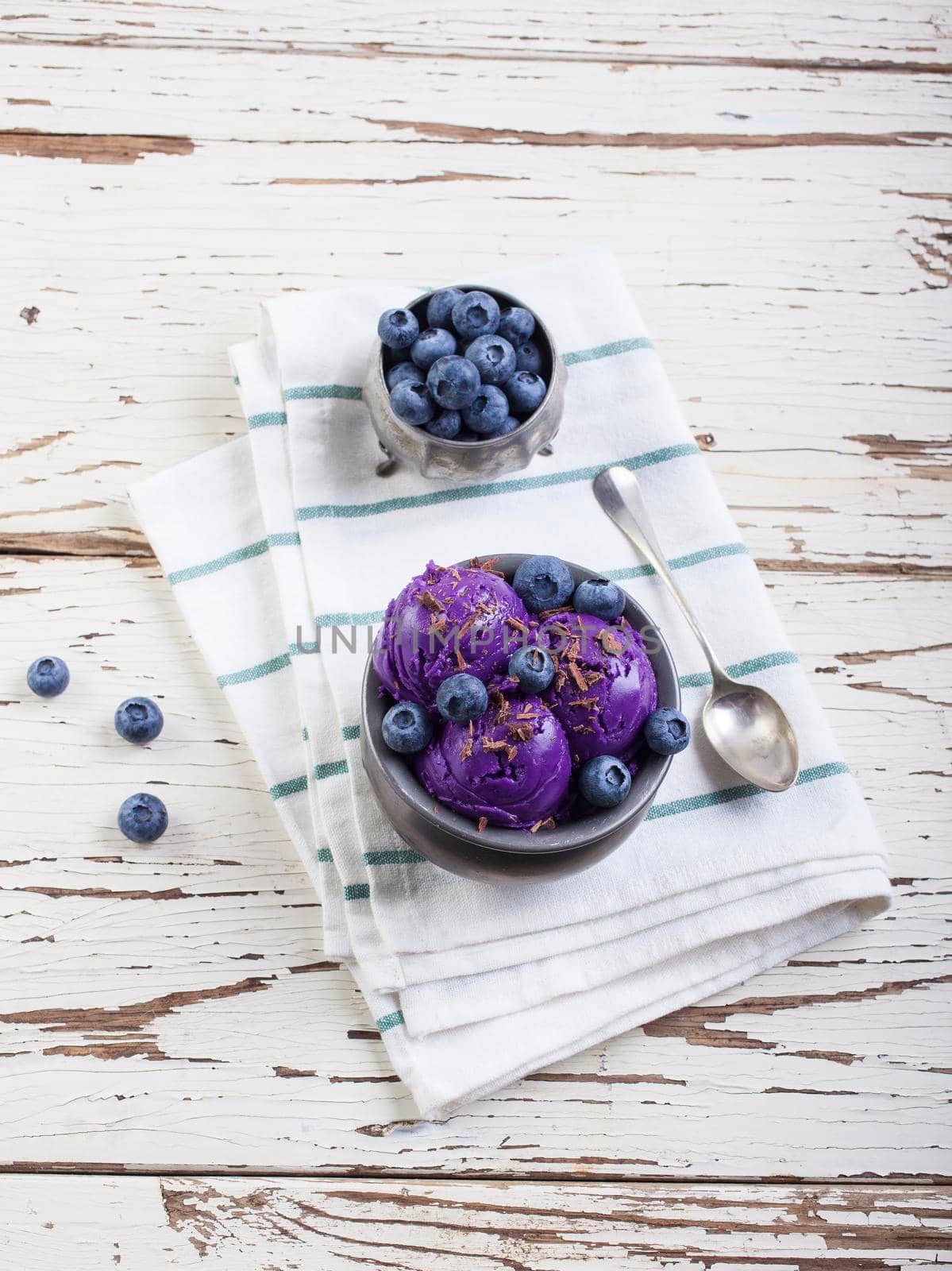 Fresh blueberry ice cream inside a pewter cup on old white wooden table