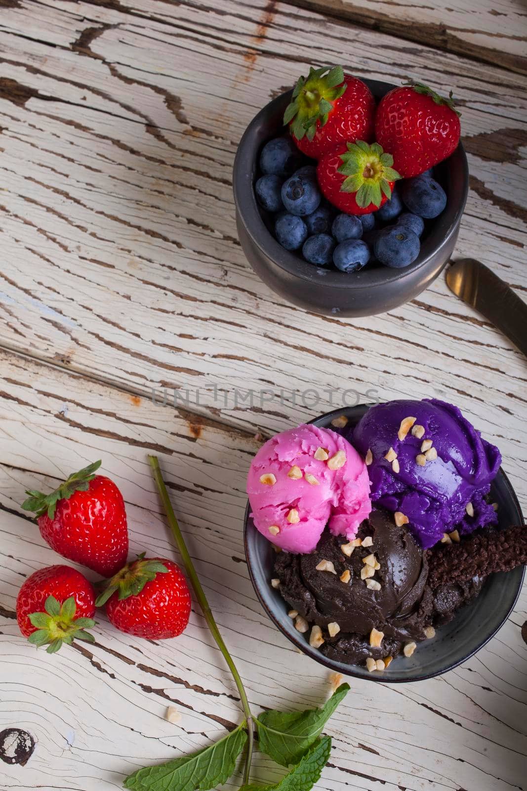 Variety of ice cream scoops in the bowls. Chocolate, strawberry and blueberry flavours