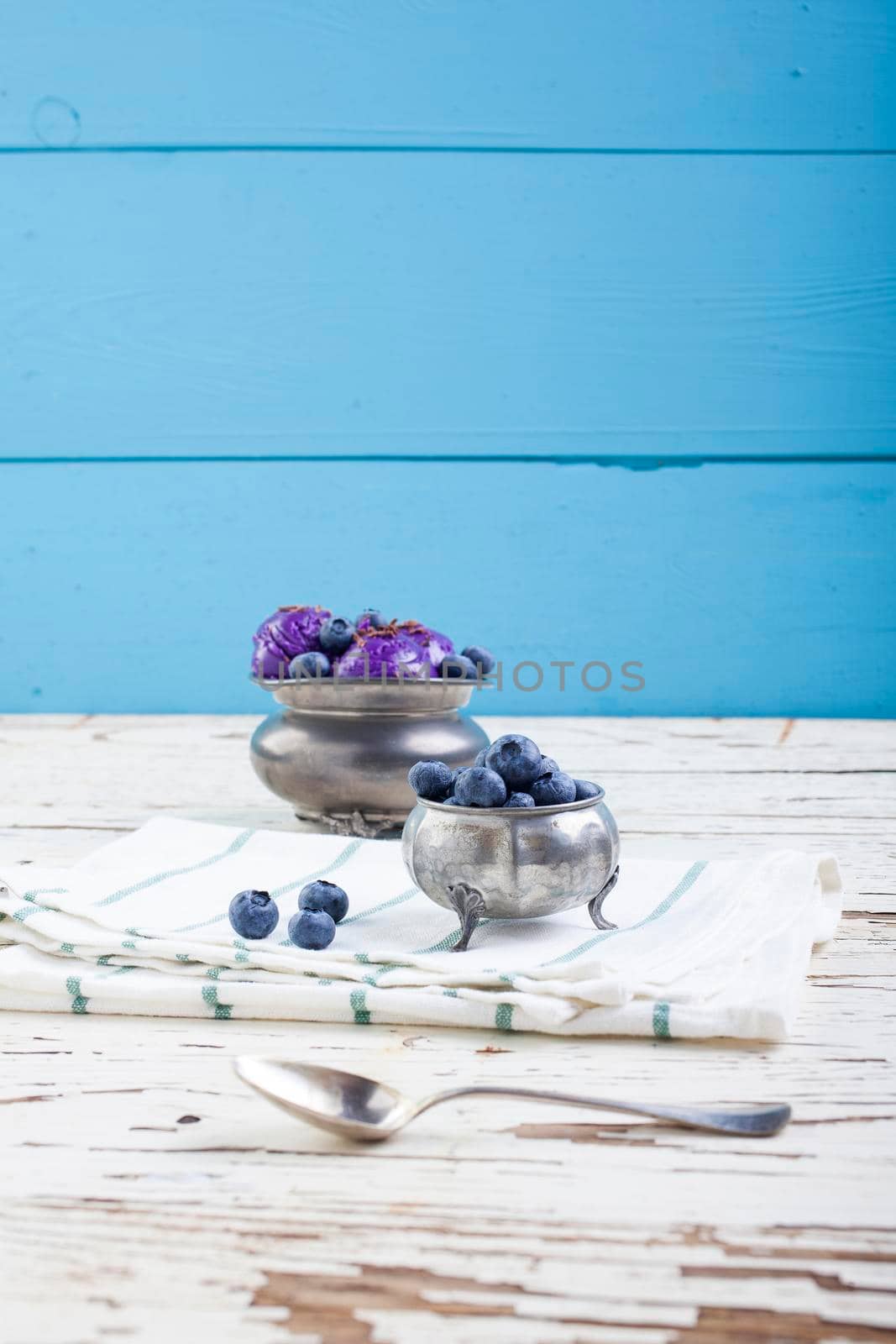 Fresh blueberry ice cream inside a pewter cup on old white wooden table