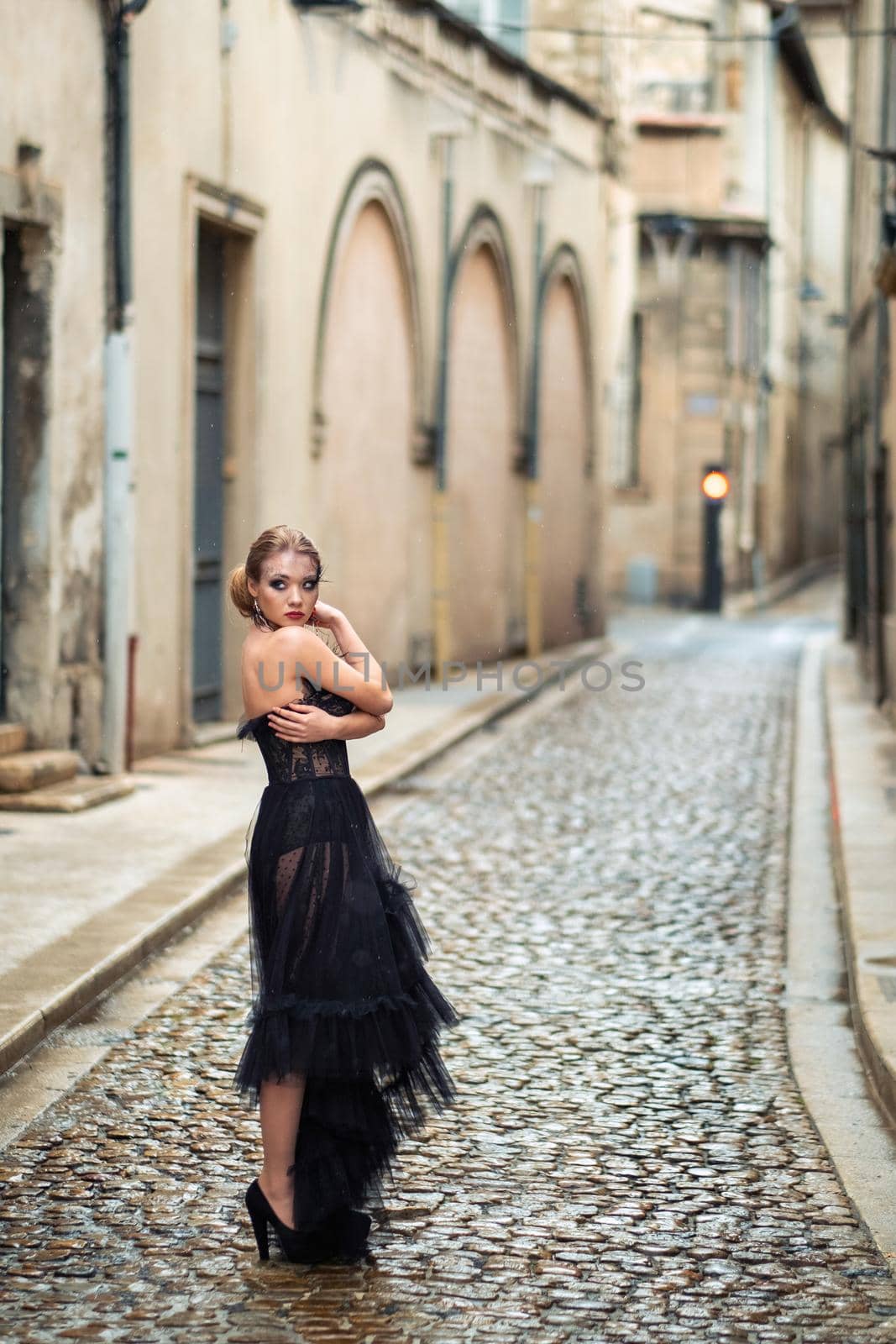 A stylish bride in a black wedding dress in the ancient French city of Avignon. A model in a black dress by Lobachad