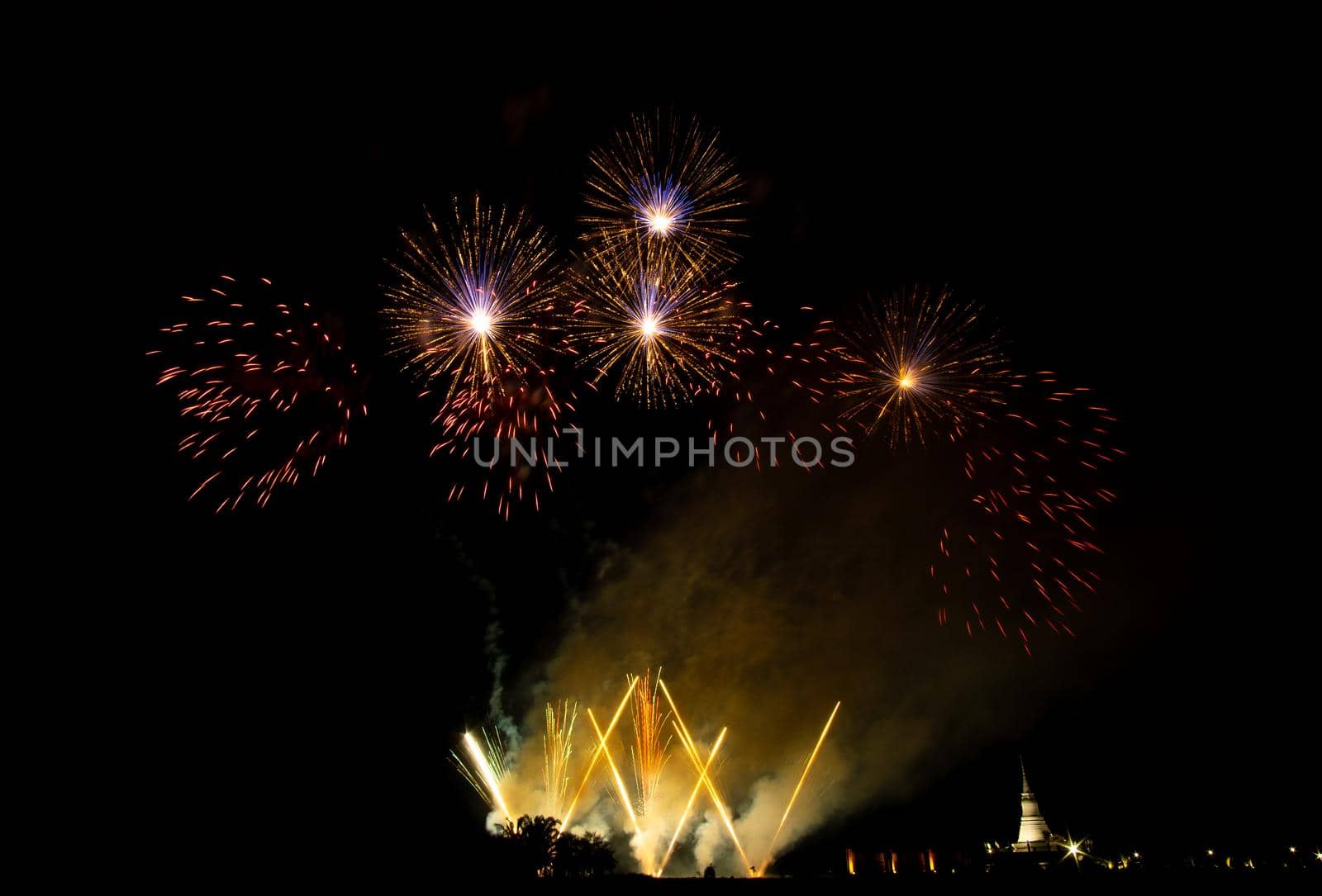 Huge, colorful fireworks over the rice fields at dusk.