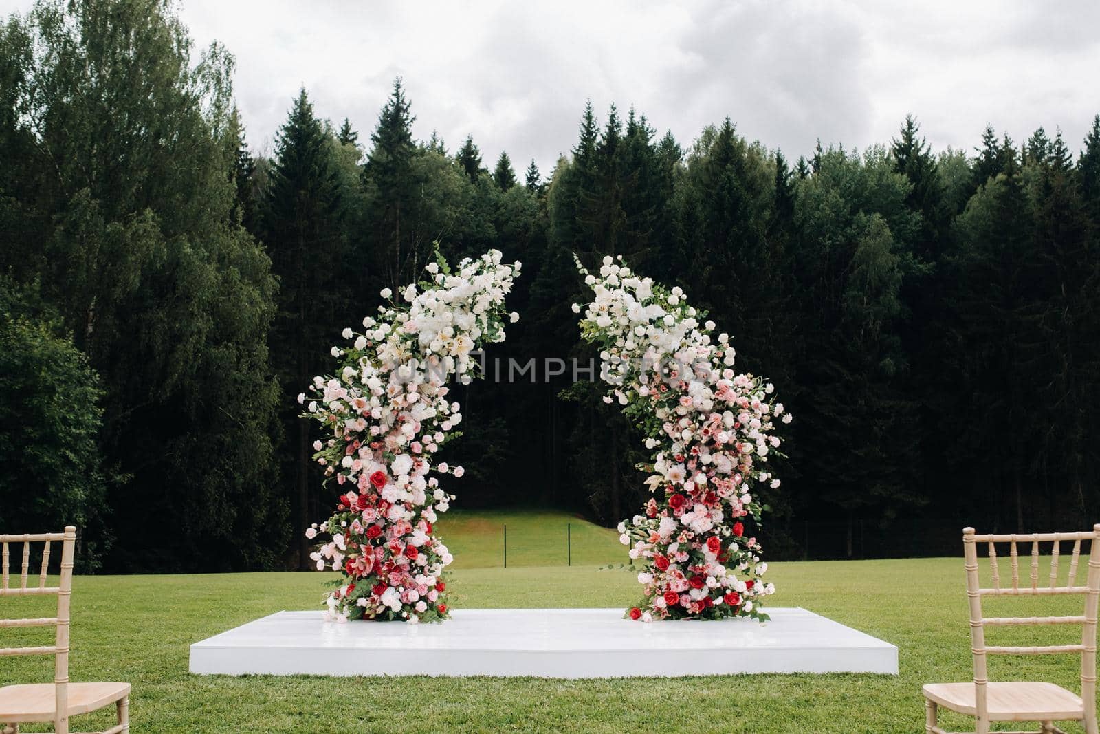 Wedding ceremony on the street on the green lawn.Decor with fresh flowers arches for the ceremony by Lobachad