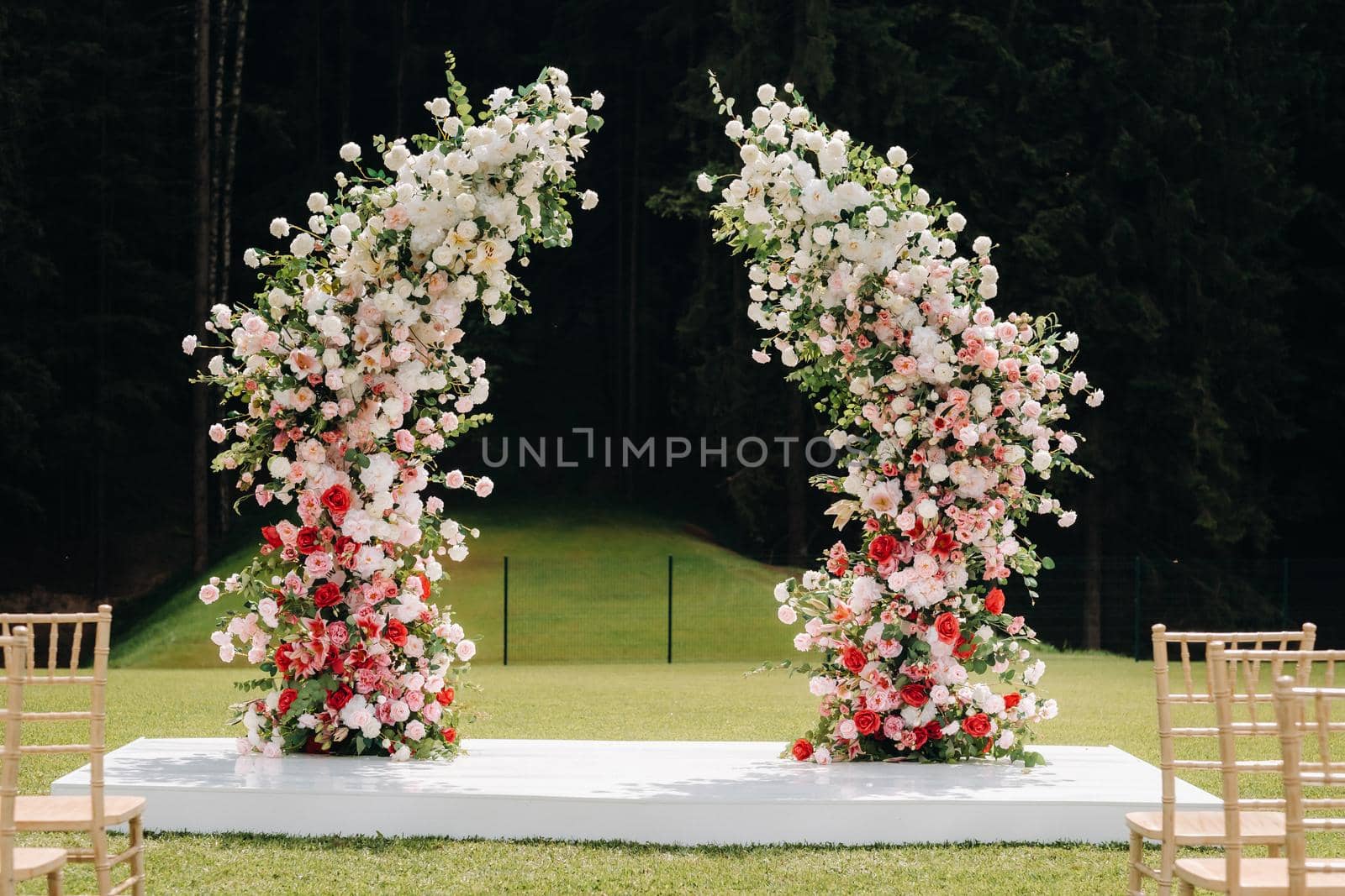 Wedding ceremony on the street on the green lawn.Decor with fresh flowers arches for the ceremony by Lobachad