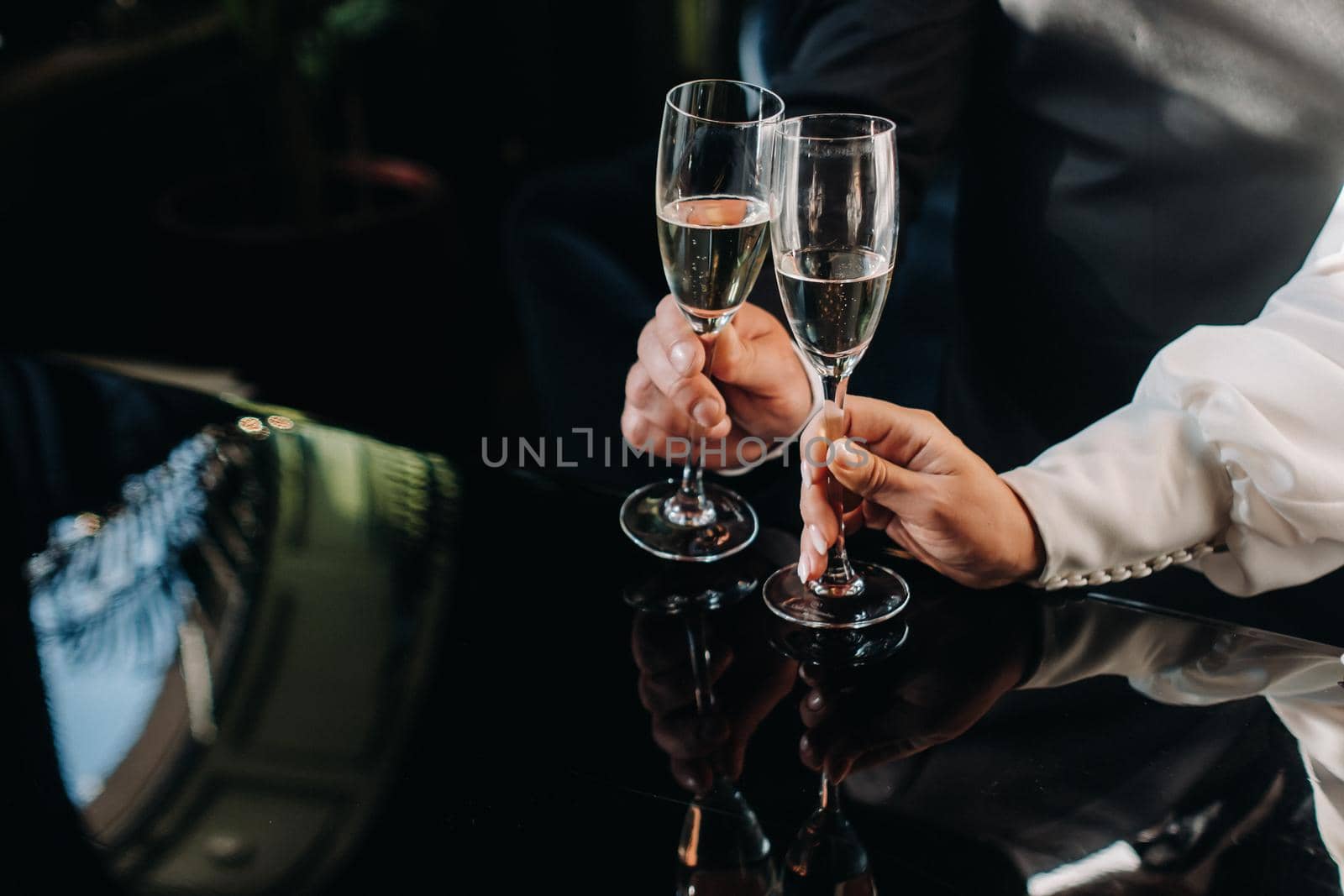 A man and a woman hold champagne glasses in their hands close-up by Lobachad