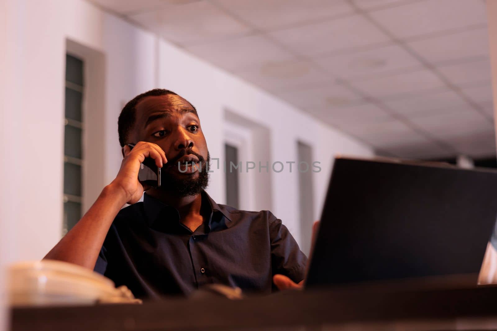Financial analyst discussing company report with colleague on smartphone, african american man answering teamlead mobile call. Corporate worker having telephone conversation in coworking space