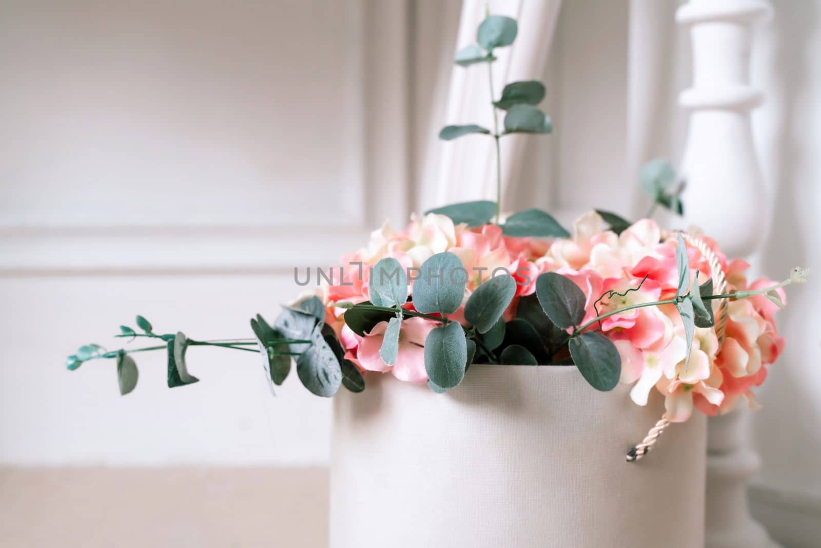 Hydrangea eucalyptus flowers bouquet in white box on white interior background.