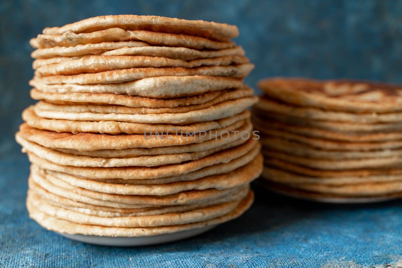 Flatbread lavash, chapati, naan, heap of tortilla on a blue background Homemade flatbread stacked. by Matiunina