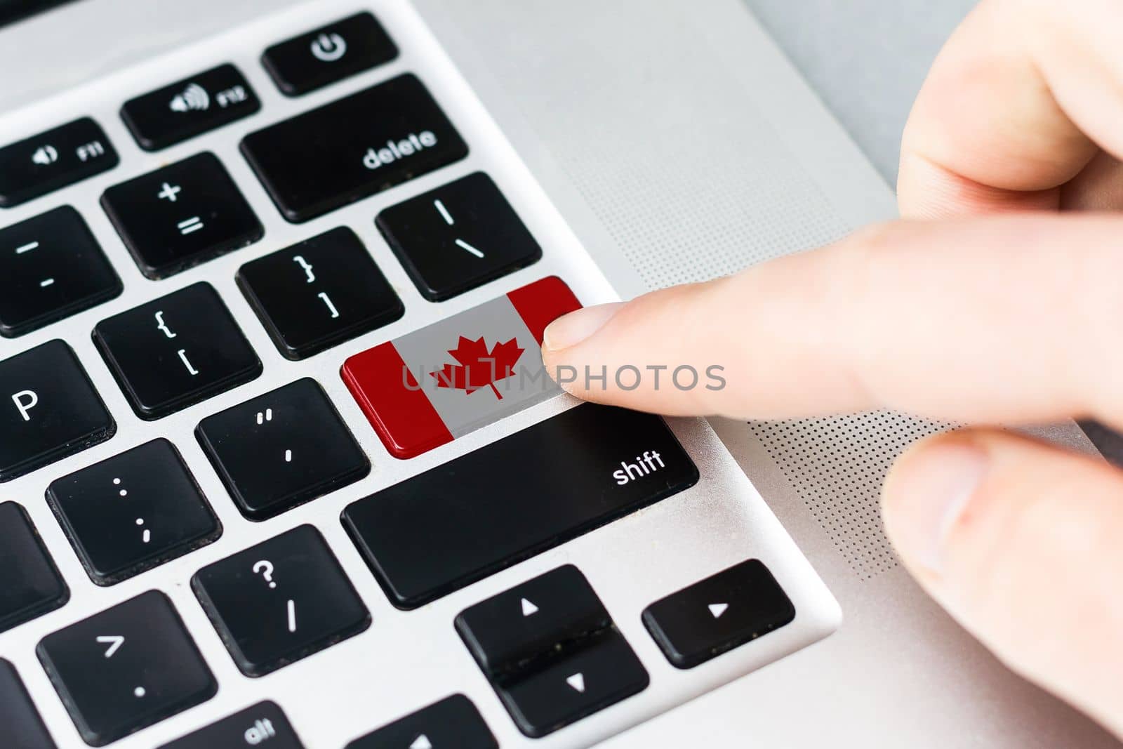 Computer key with the Canada on it. Male hand pressing computer key with Canada flag. by Andelov13