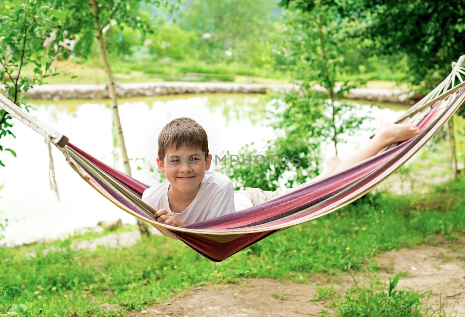 Cheerful boy playing in a hammock on the nature