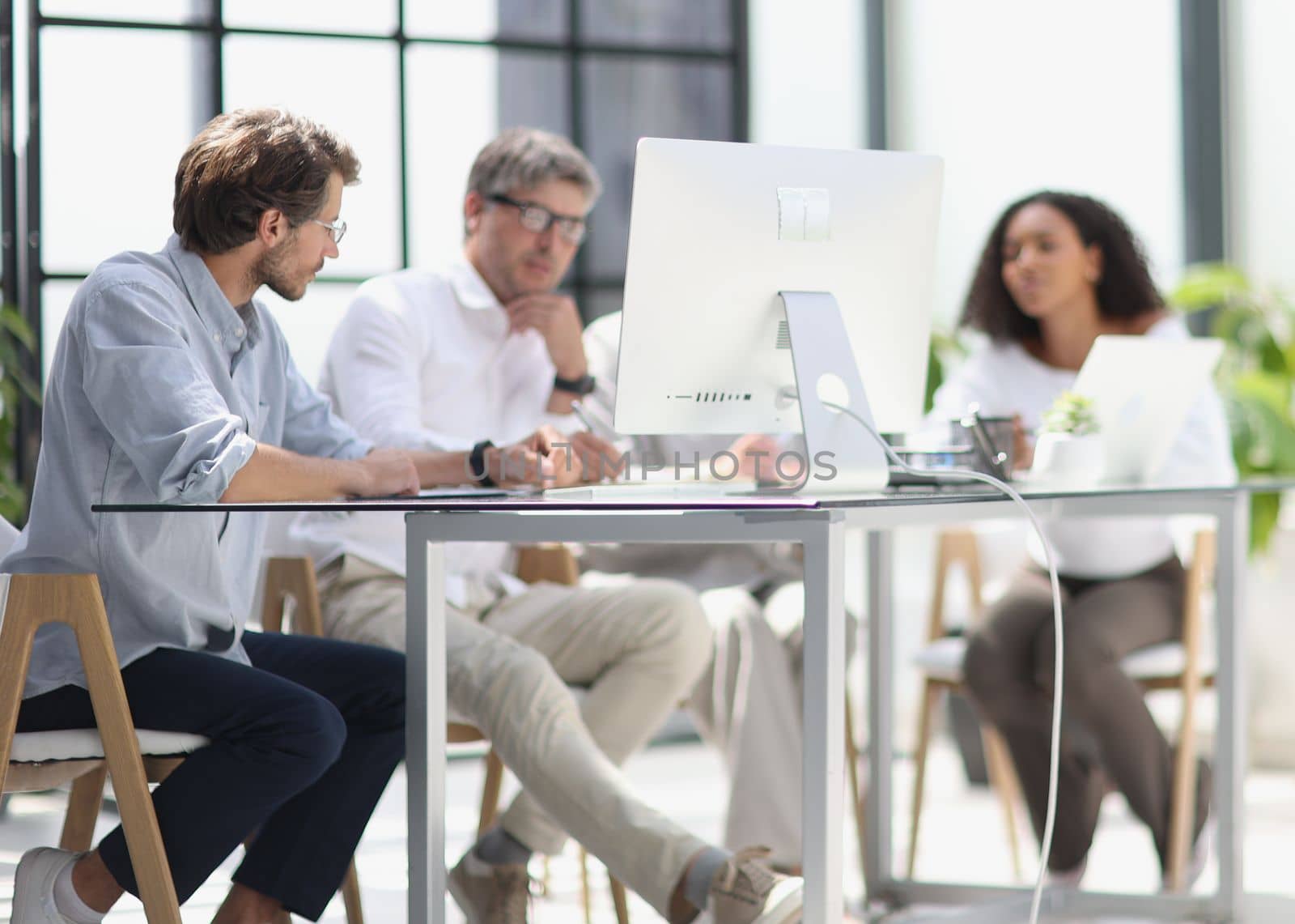 discussion of business people in the office sitting at the table looking at the monitor