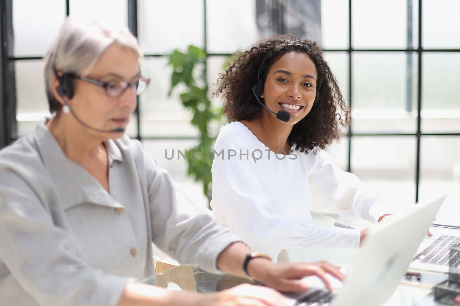 Young friendly operator woman agent with headsets working in a call centre