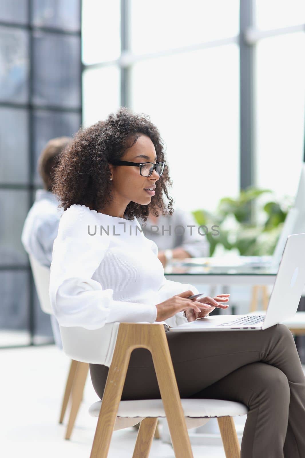 young attractive african american woman in the office sitting at a laptop