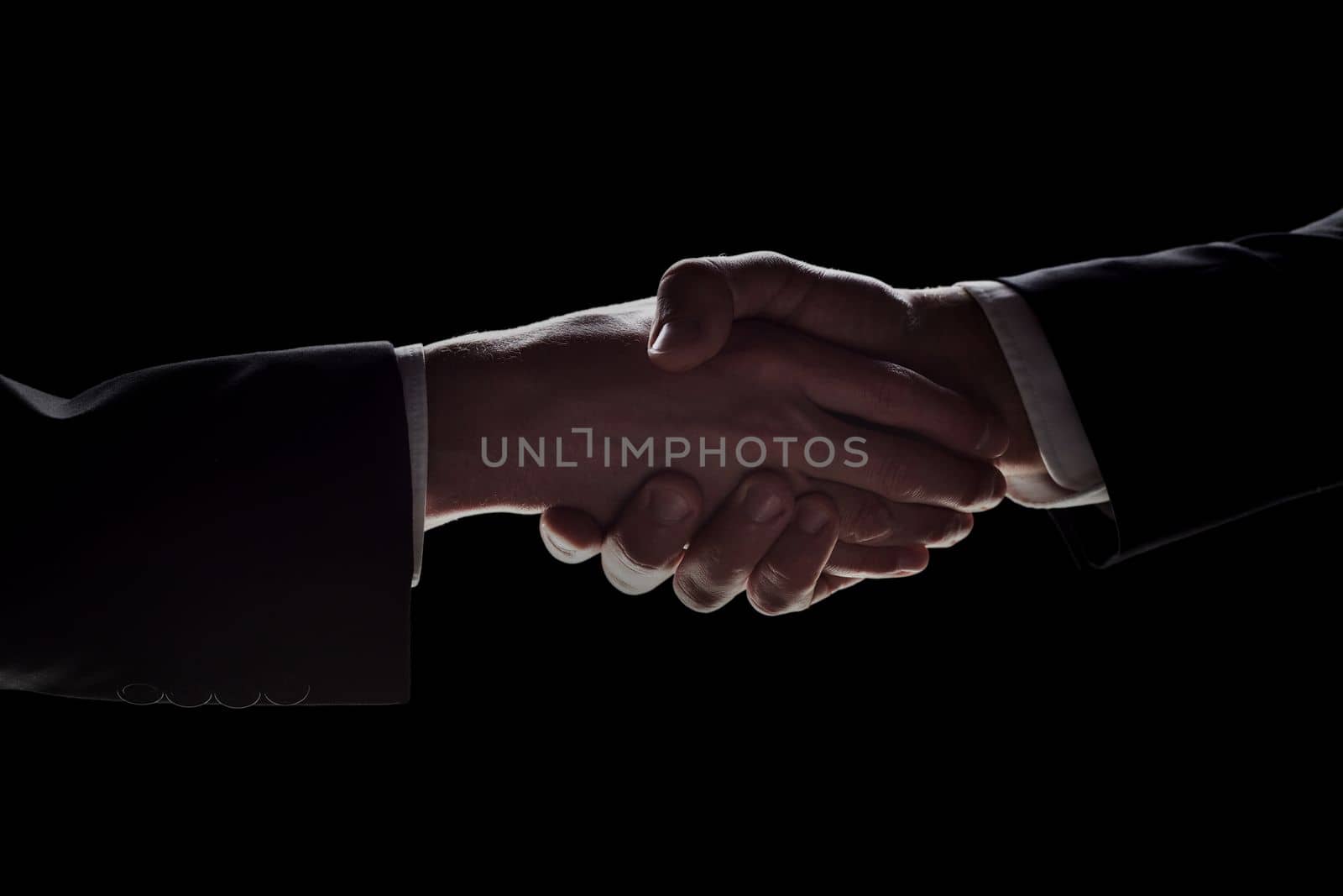 Photo of two men in suits shaking hands on a black background