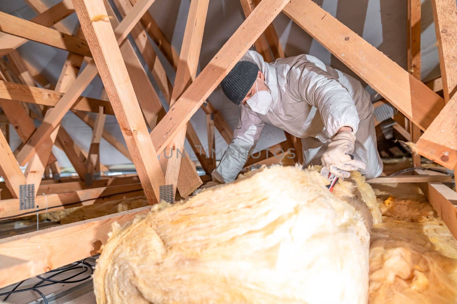 man insulates the roof and ceiling of the house with glass wool by Edophoto