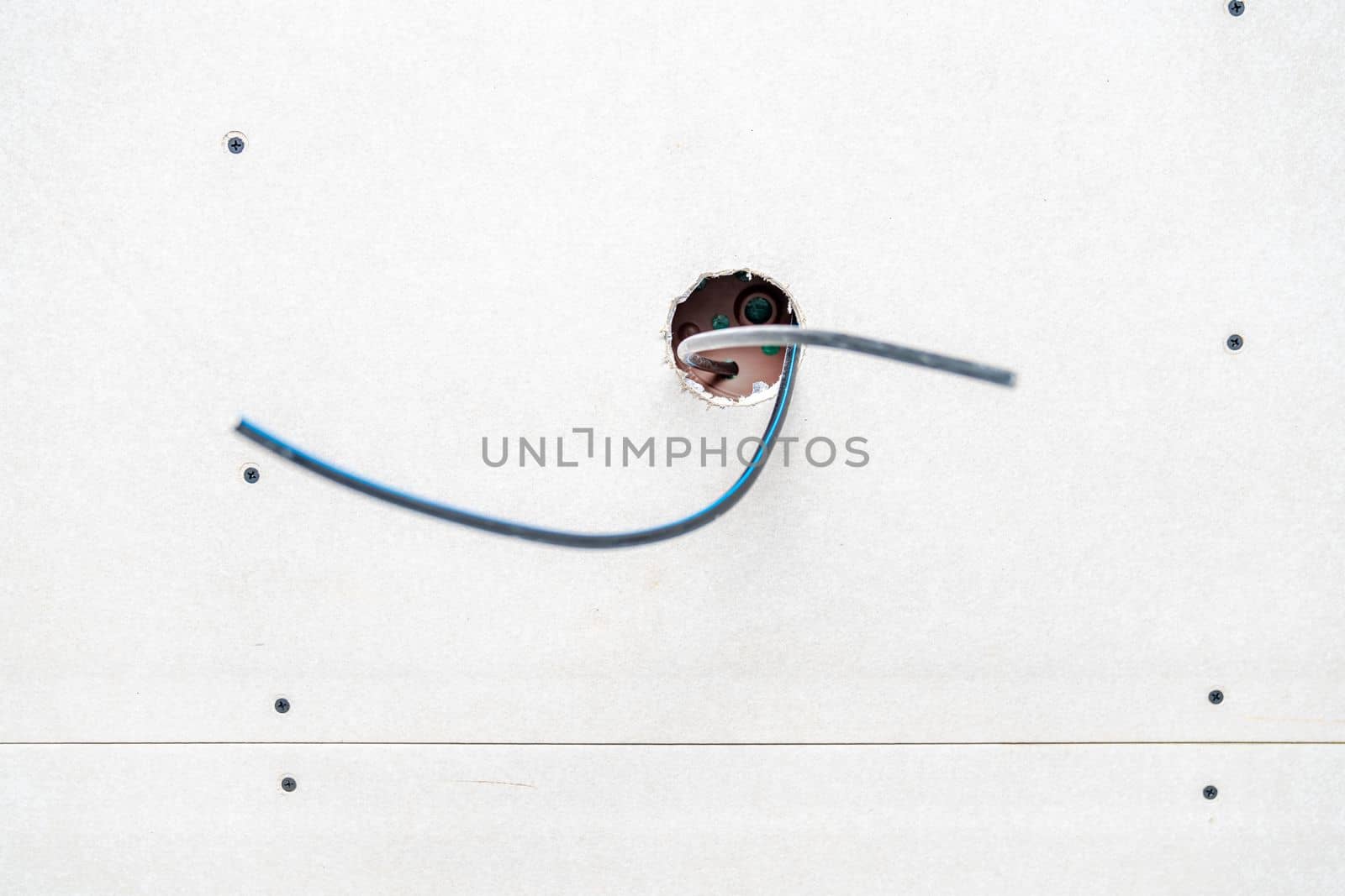 wires in the hole in the ceiling to connect the light. High quality photo
