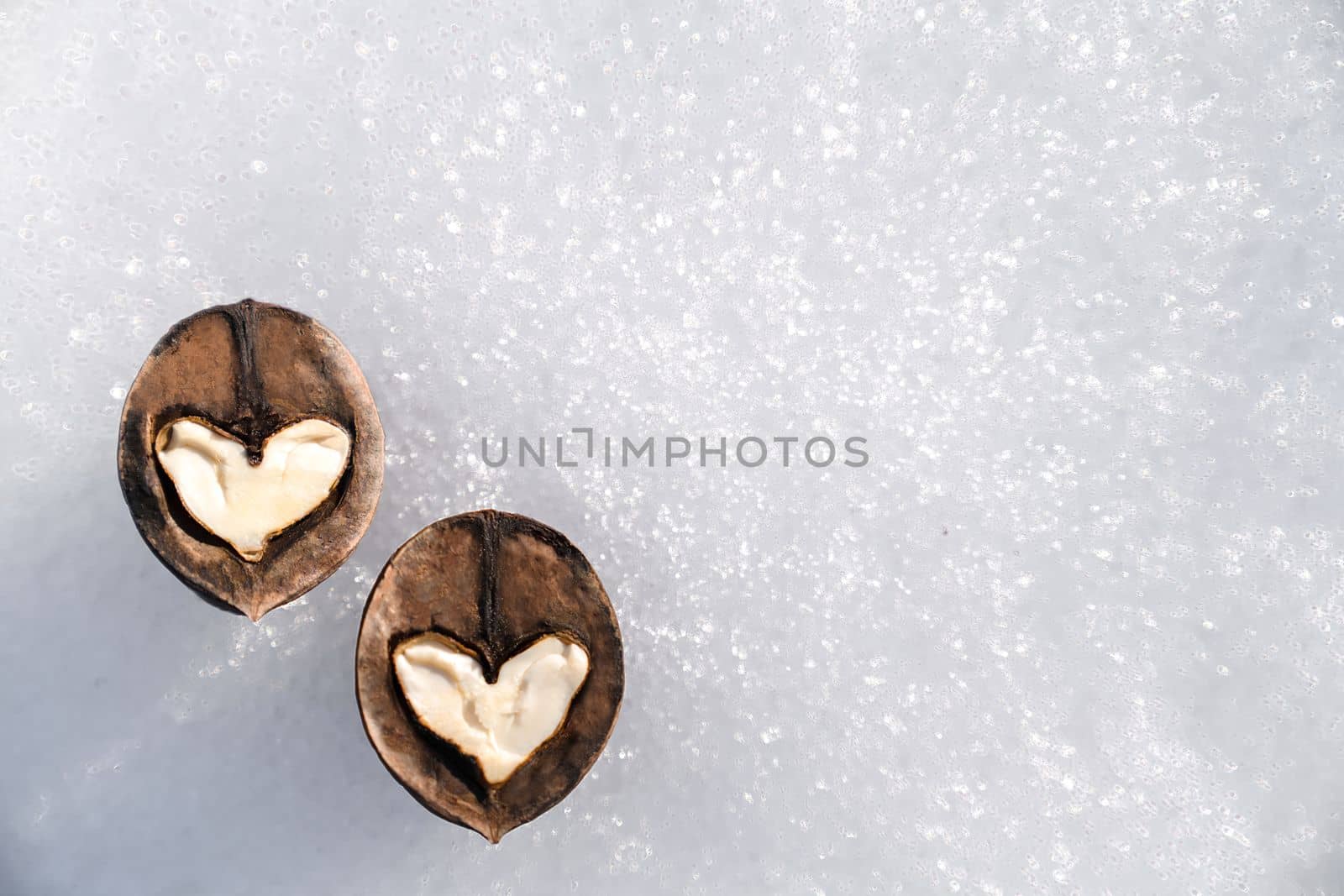 Two white hearts made of walnut halves against background of white snow, concept of love, copy space by Laguna781