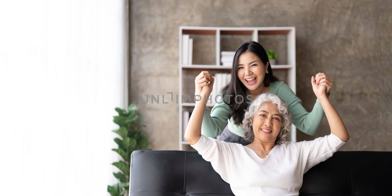 Happy daughter and mother having fun in living room, smiling mother hugging young grown daughter bonding chatting relaxing encourage each other at home together.