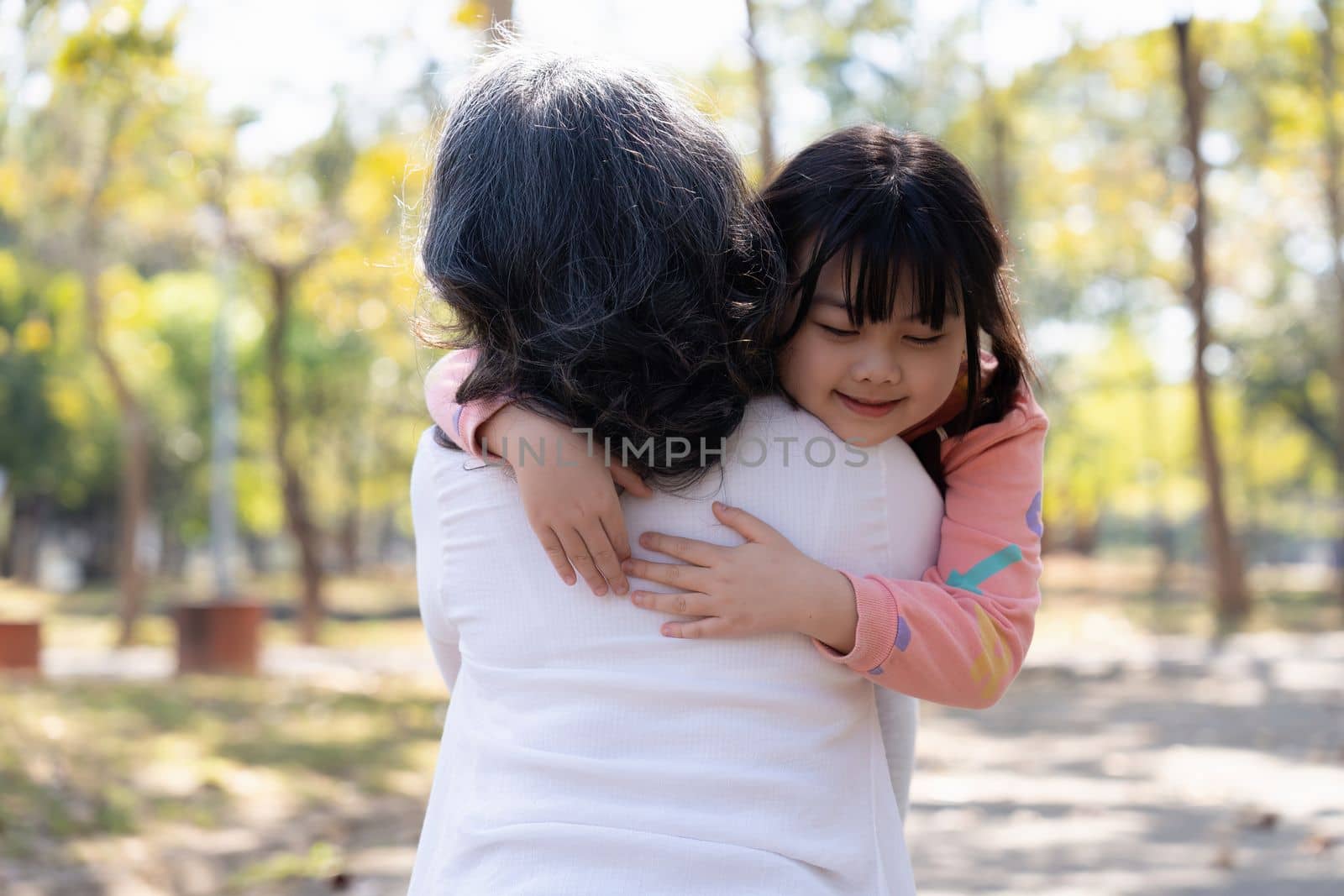 An cute ,granddaughter giving hug, cuddling to her grandmother, having great time in the park together.
