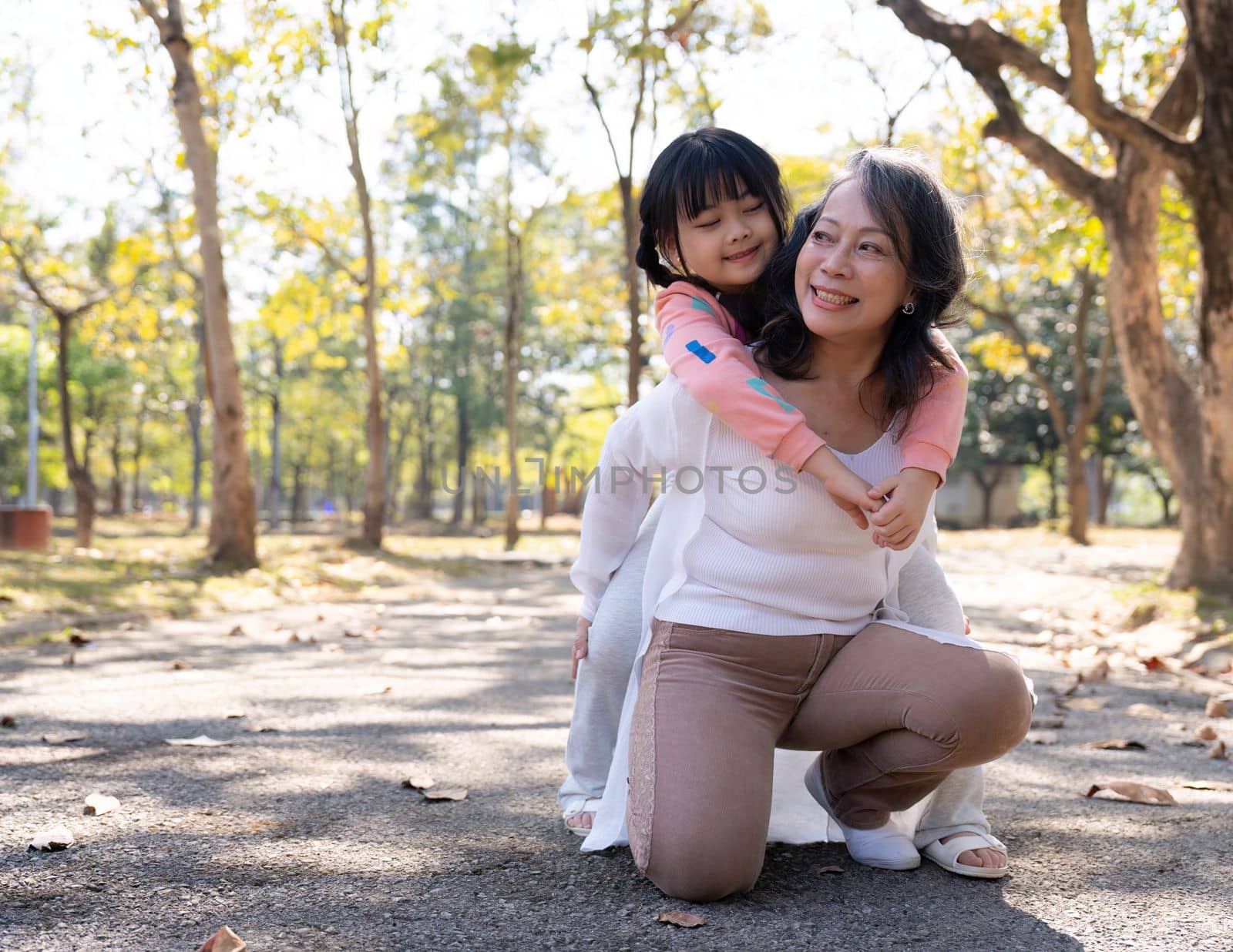 Happy grandmother and grandchild walking in public park.