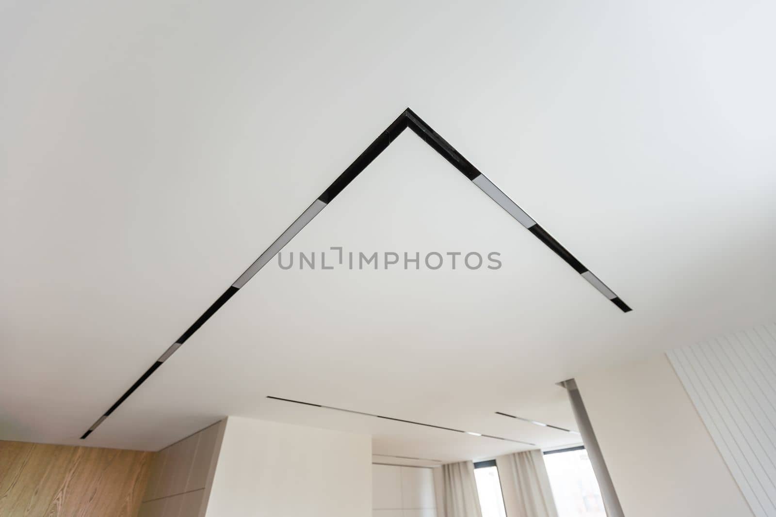 LED strip light and illumination. Also called ribbon light or LED tape to suspended on ceiling in plasterboard in empty living room include down light, white wall. Interior home design and technology by Andelov13