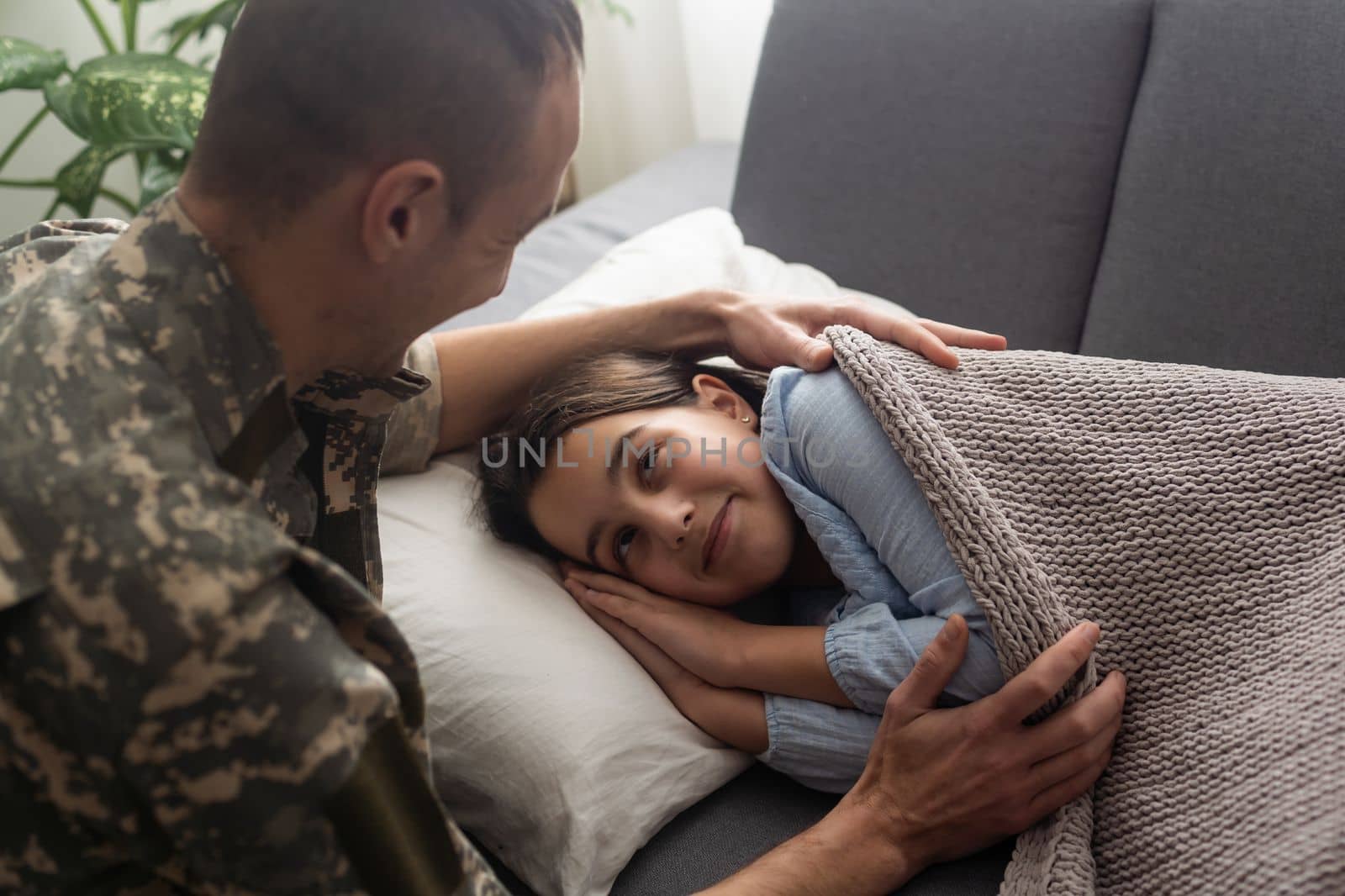 Soldier kissing his daughter while she sleeping on a bed at home