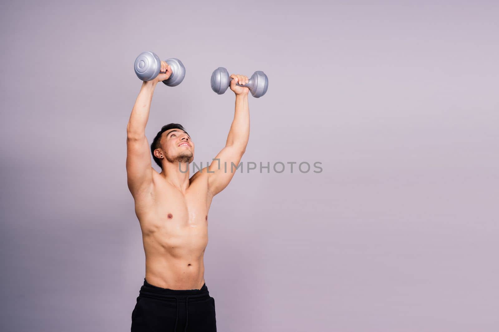 Shirtless bodybuilder showing his great body and holding dumbells.