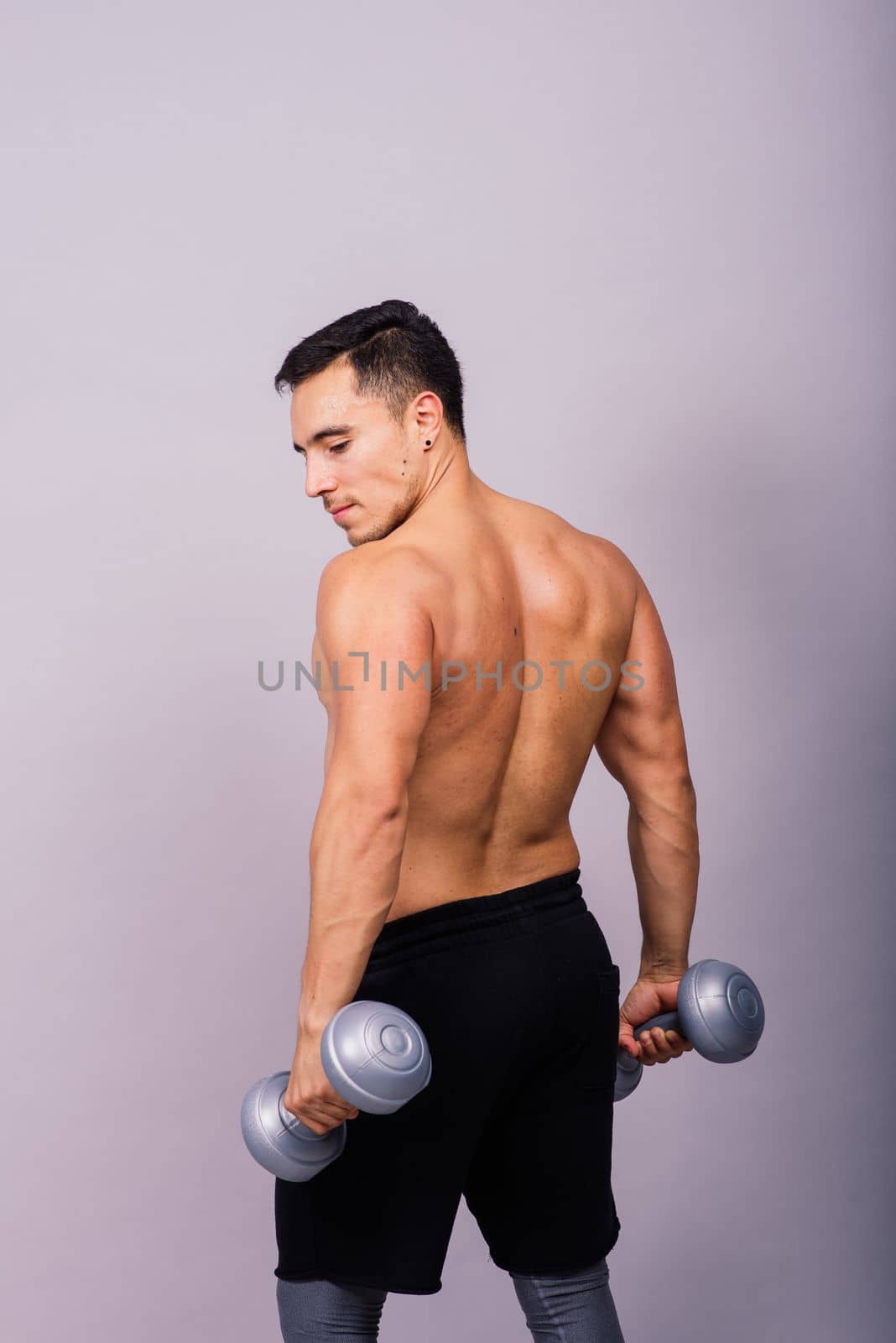 Shirtless bodybuilder showing his great body and holding dumbells.