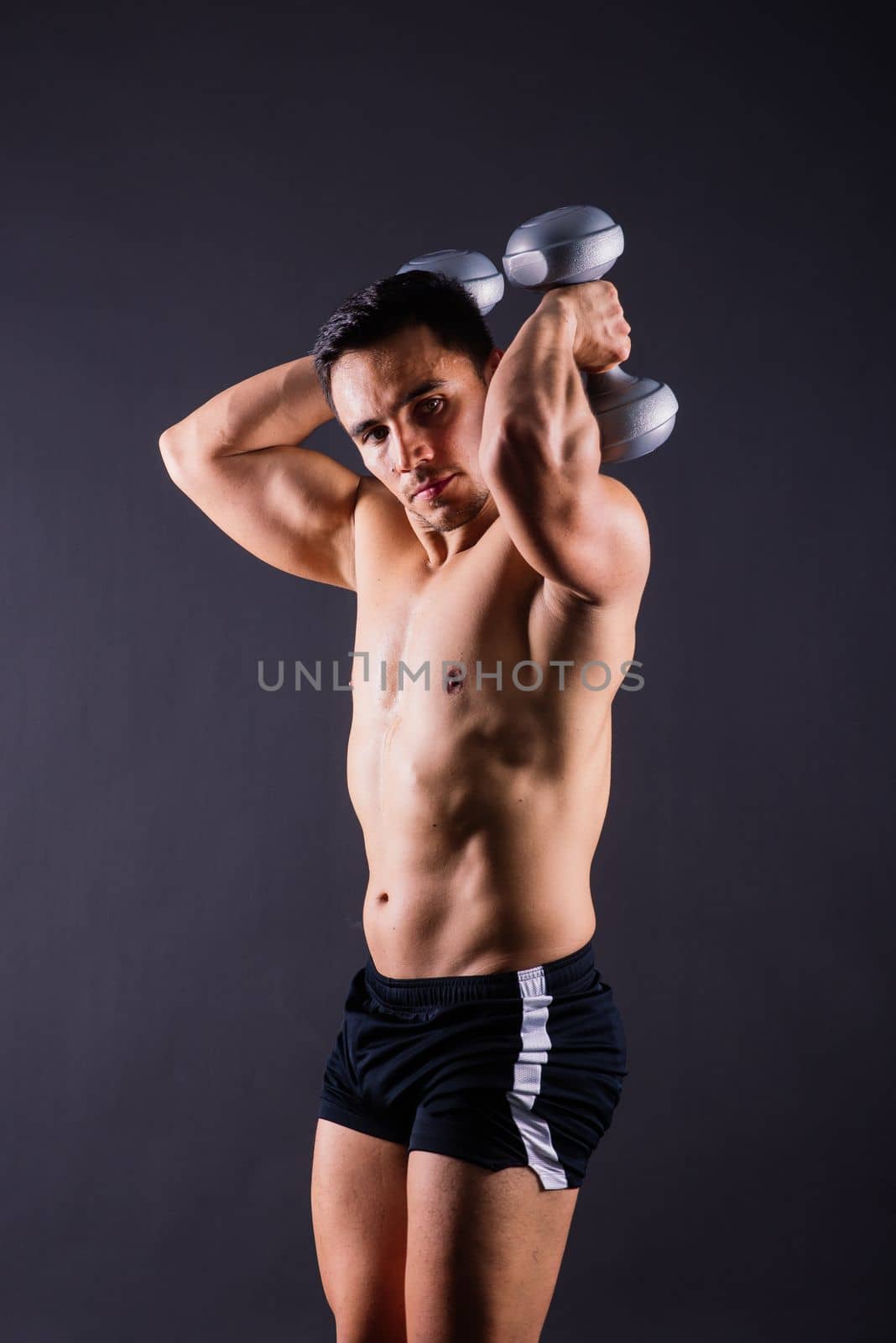 Shirtless bodybuilder showing his great body and holding dumbell. by Zelenin