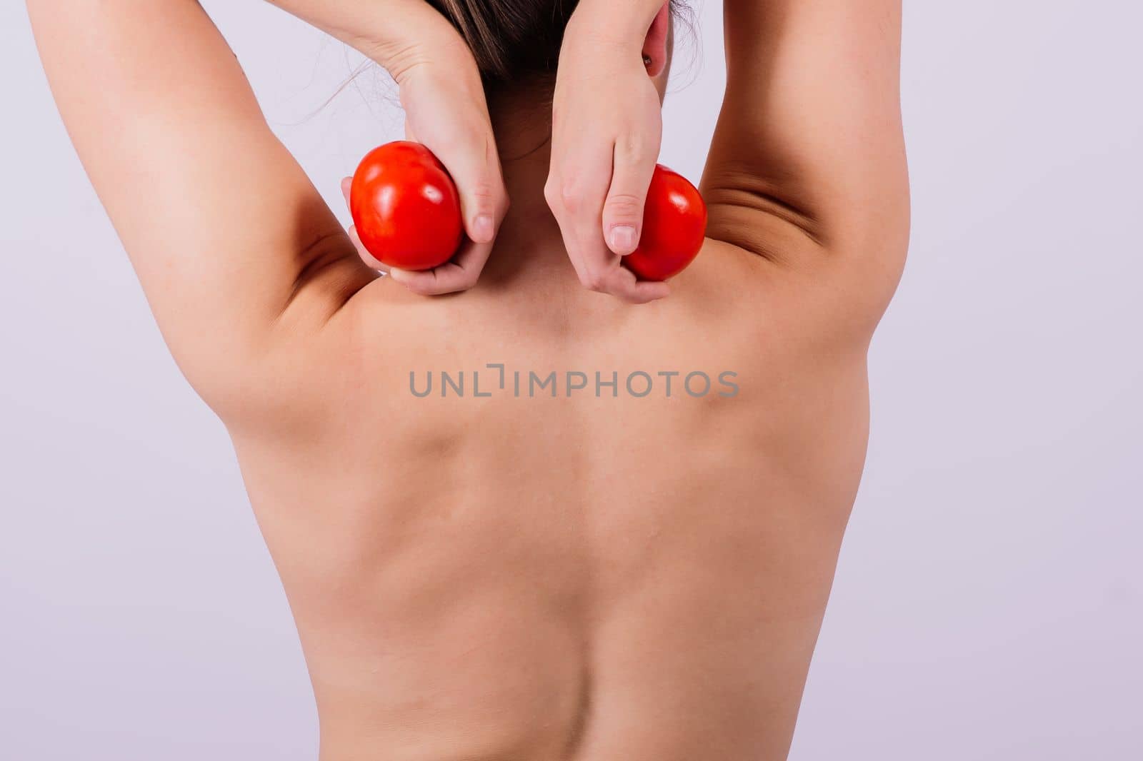 Healthy young woman holding tomatos over her eyes, laughing, bare shoulders, topless. by Zelenin