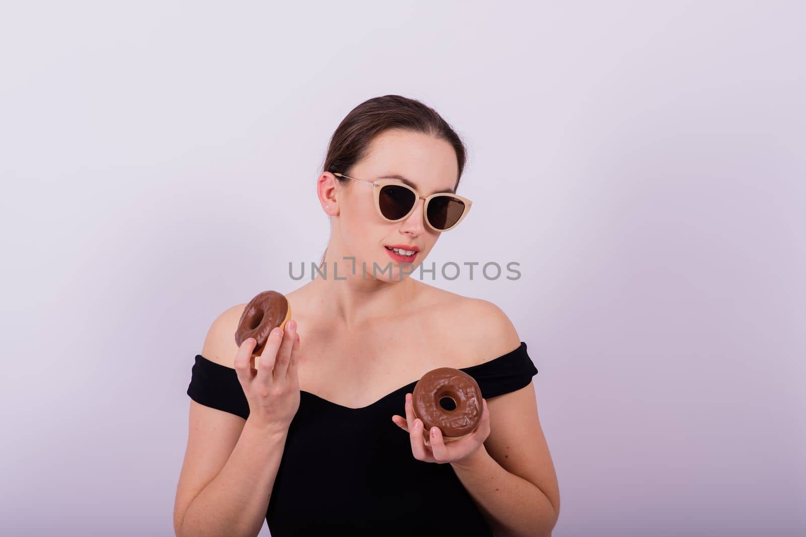Close up shot of nude woman's body with chocolate covered donuts